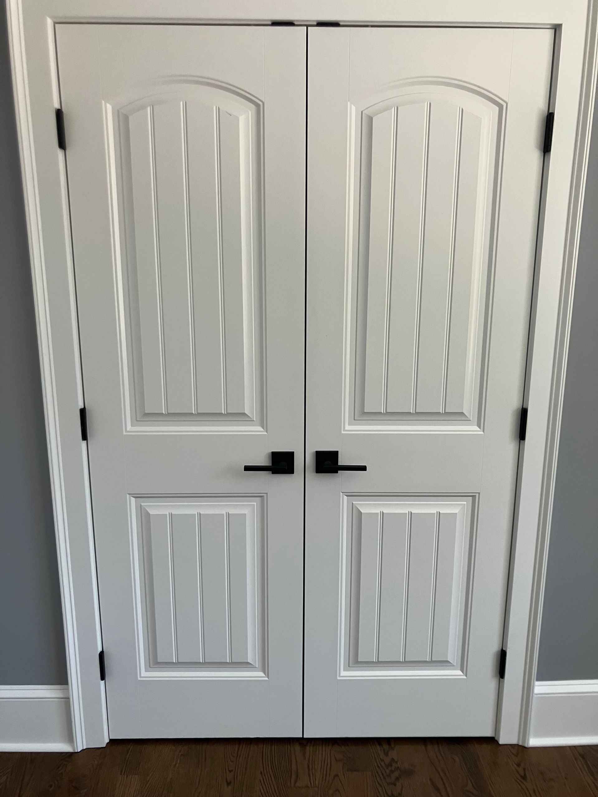 A pair of white doors with black handles in a room.