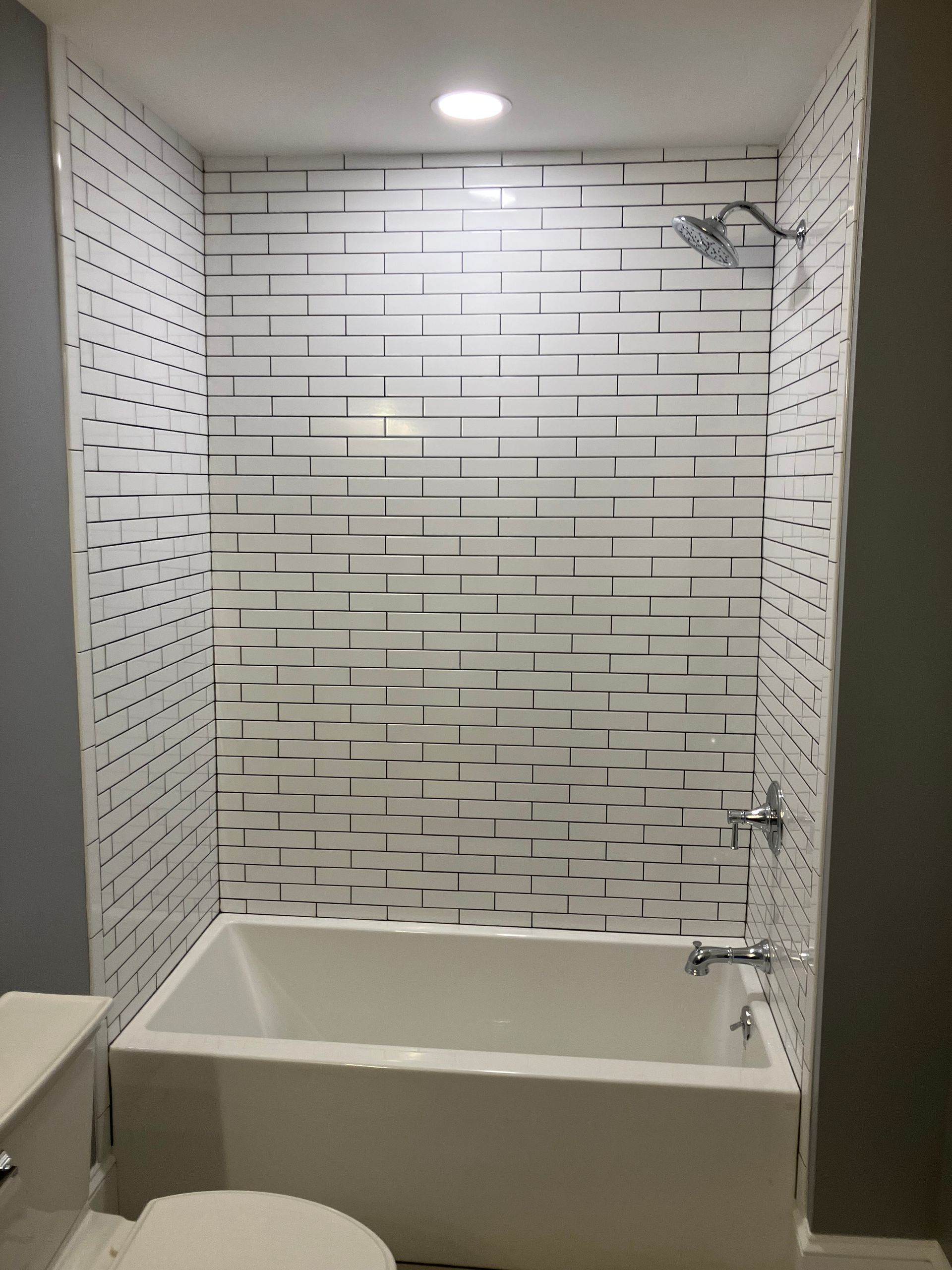 A bathroom with a bathtub , toilet and shower.