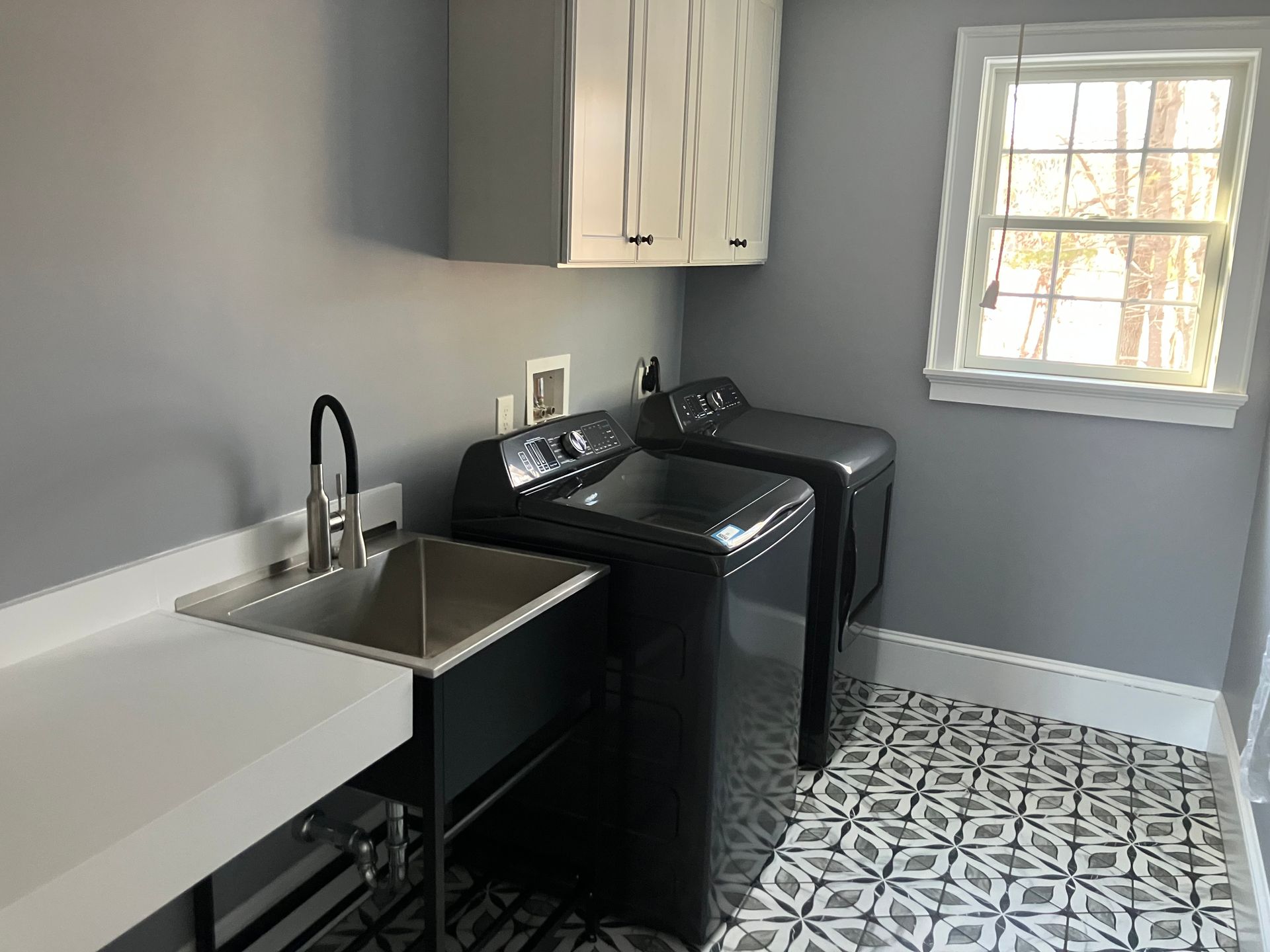 A laundry room with a sink , washer and dryer , and a window.