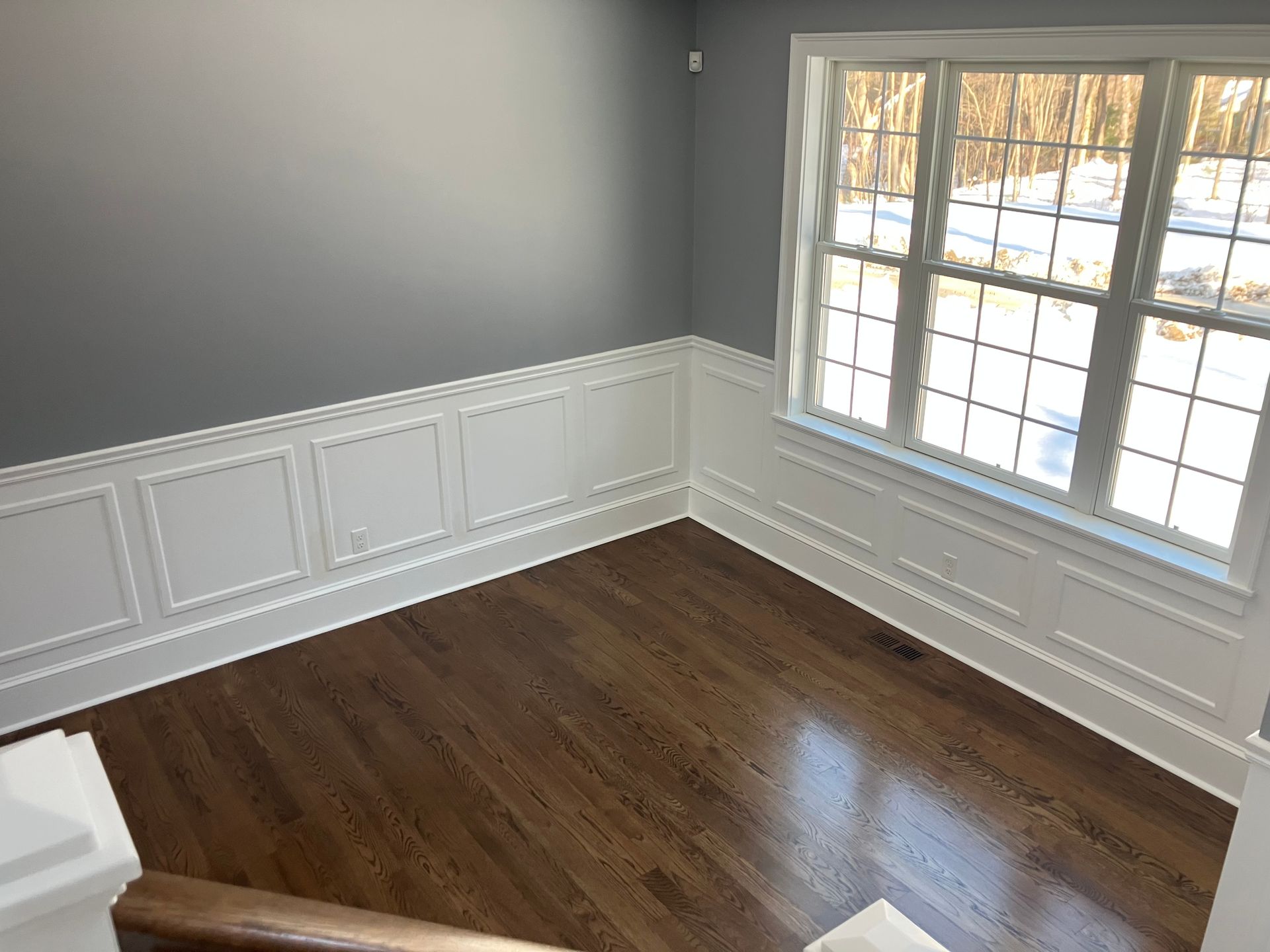 An empty room with hardwood floors and two windows.