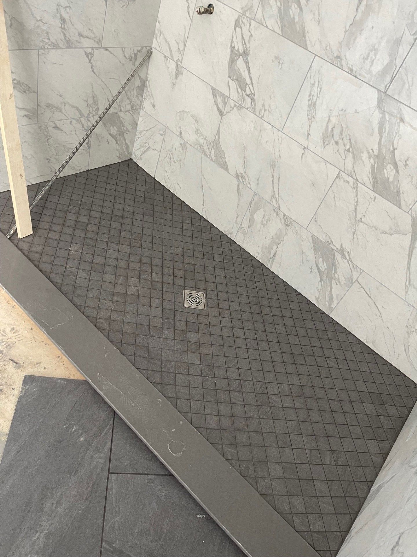 A shower stall is being built in a bathroom with marble tiles.