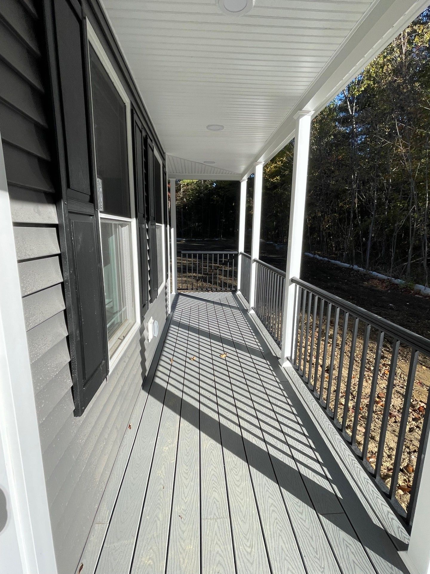 A porch with a railing and shutters on a house