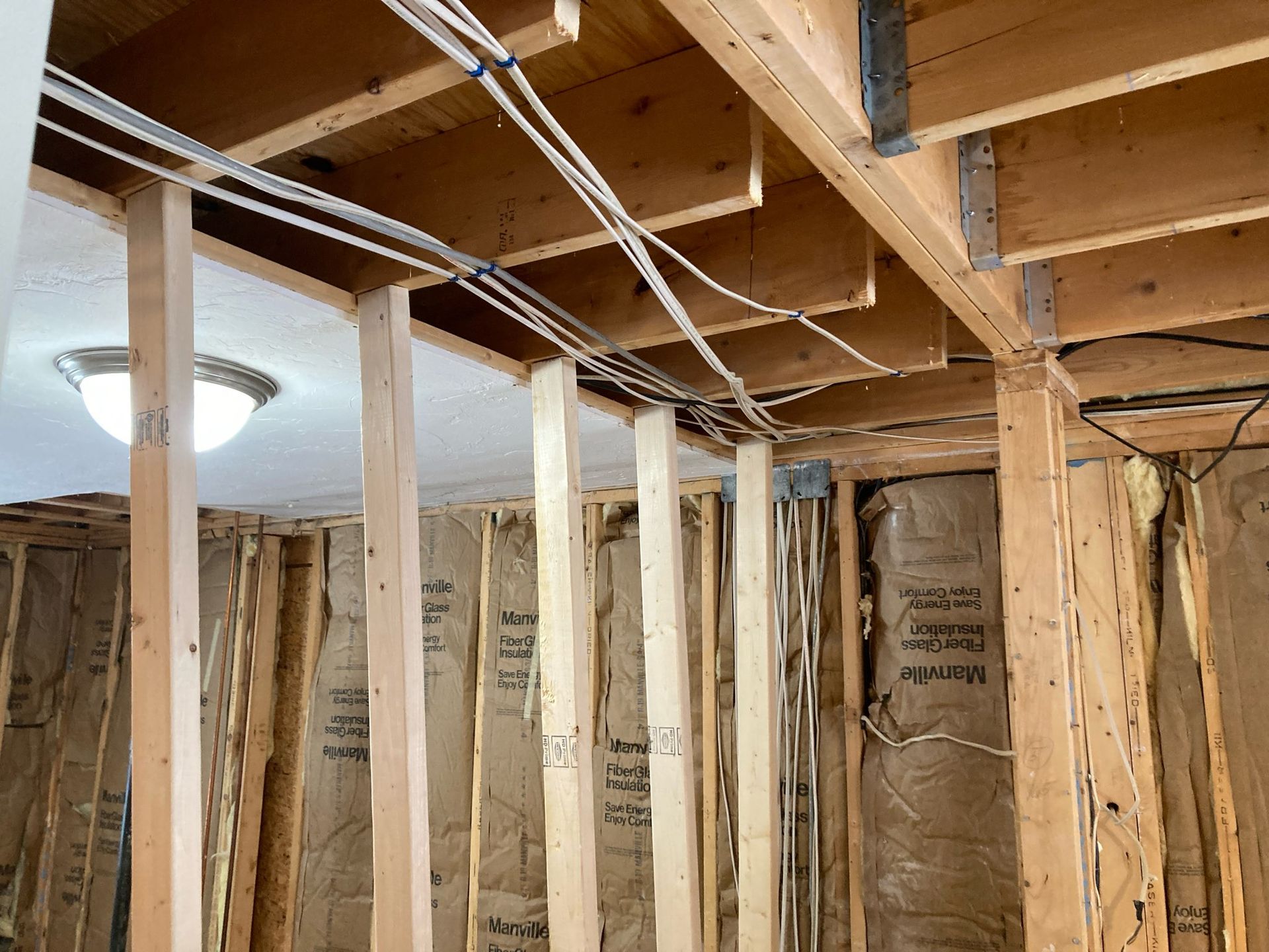 A house is being built with wooden beams and wires hanging from the ceiling.