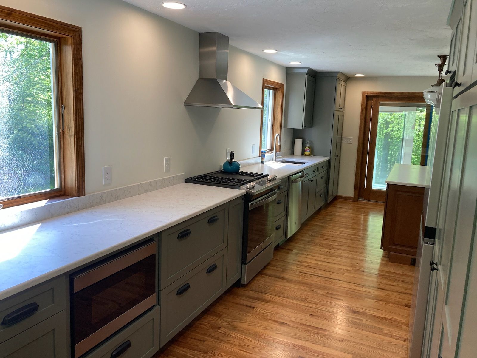 A kitchen with stainless steel appliances and wooden floors.