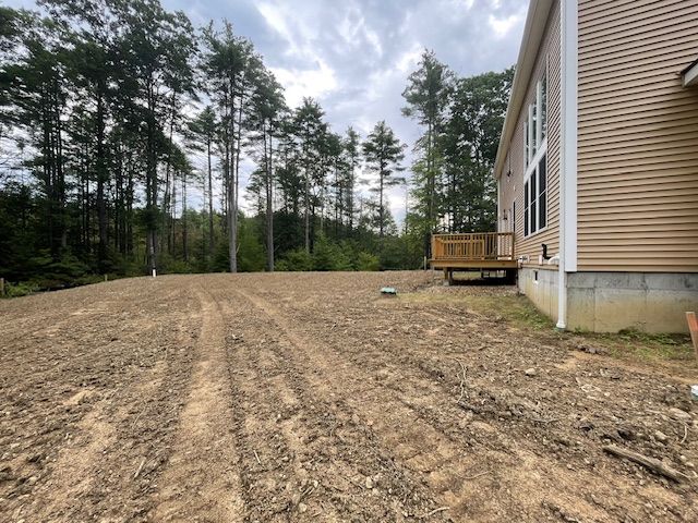 A house in the middle of a dirt field with trees in the background