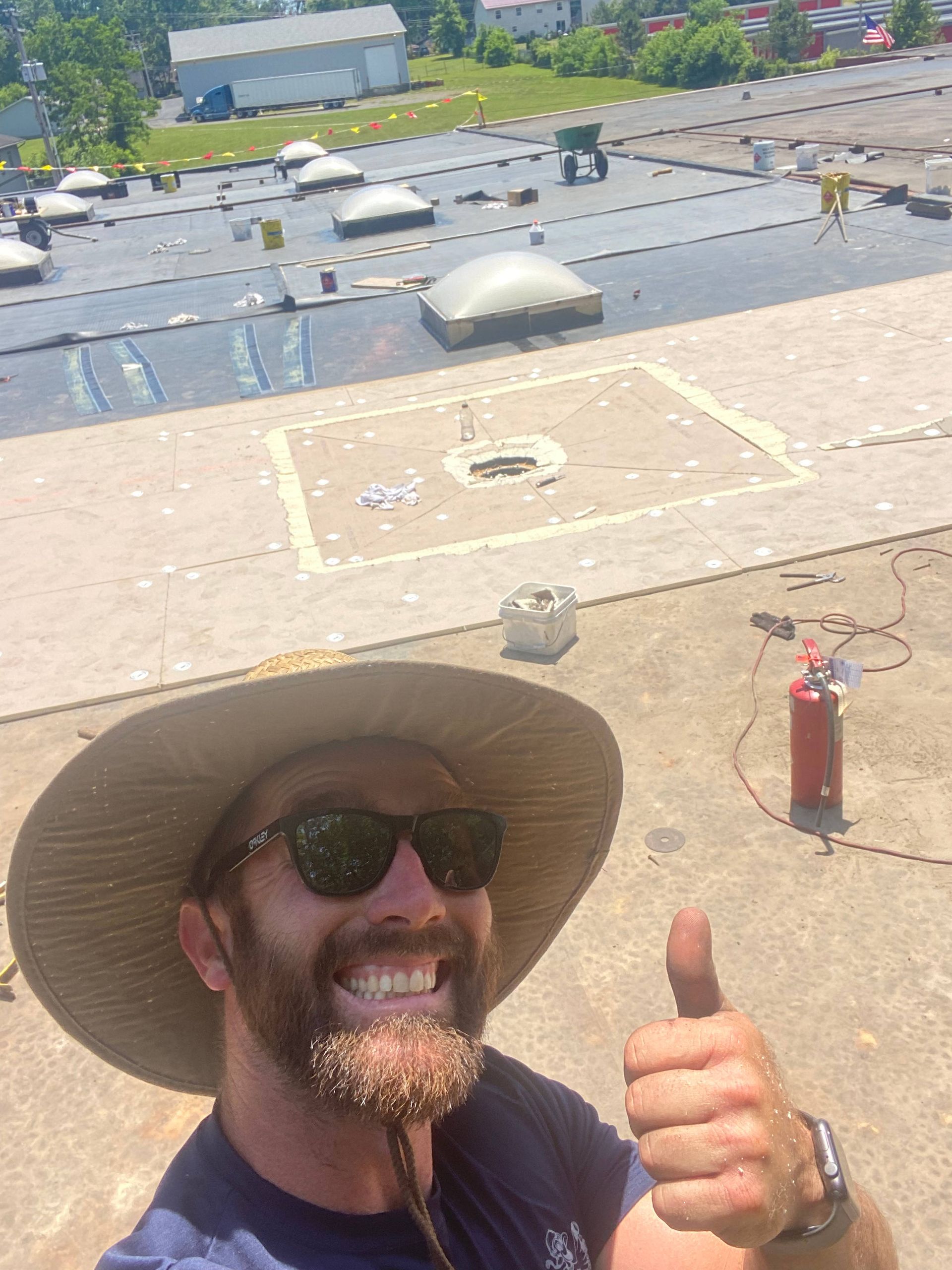 A man wearing a hat and sunglasses is giving a thumbs up