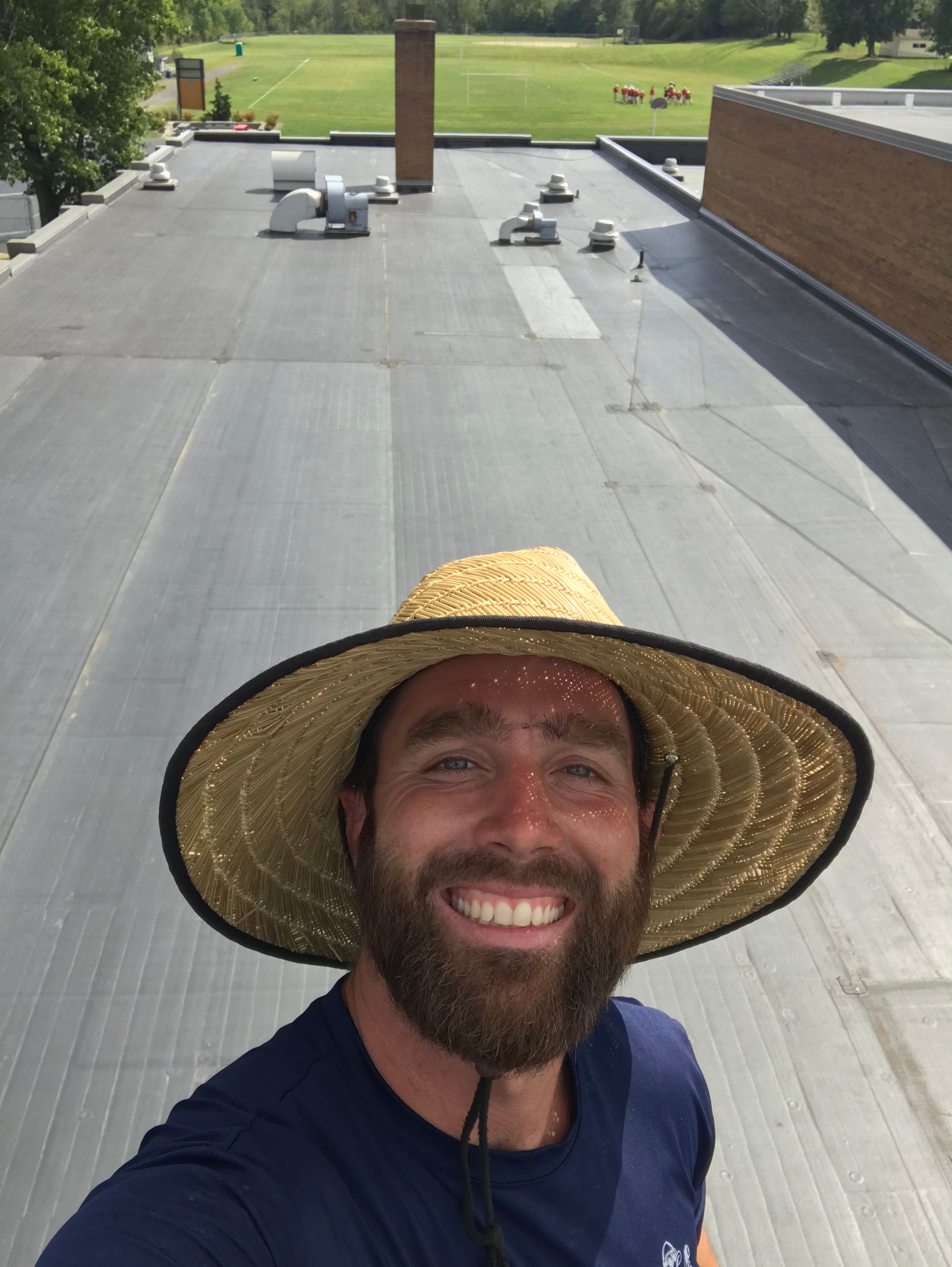 A man wearing a straw hat is standing on a roof