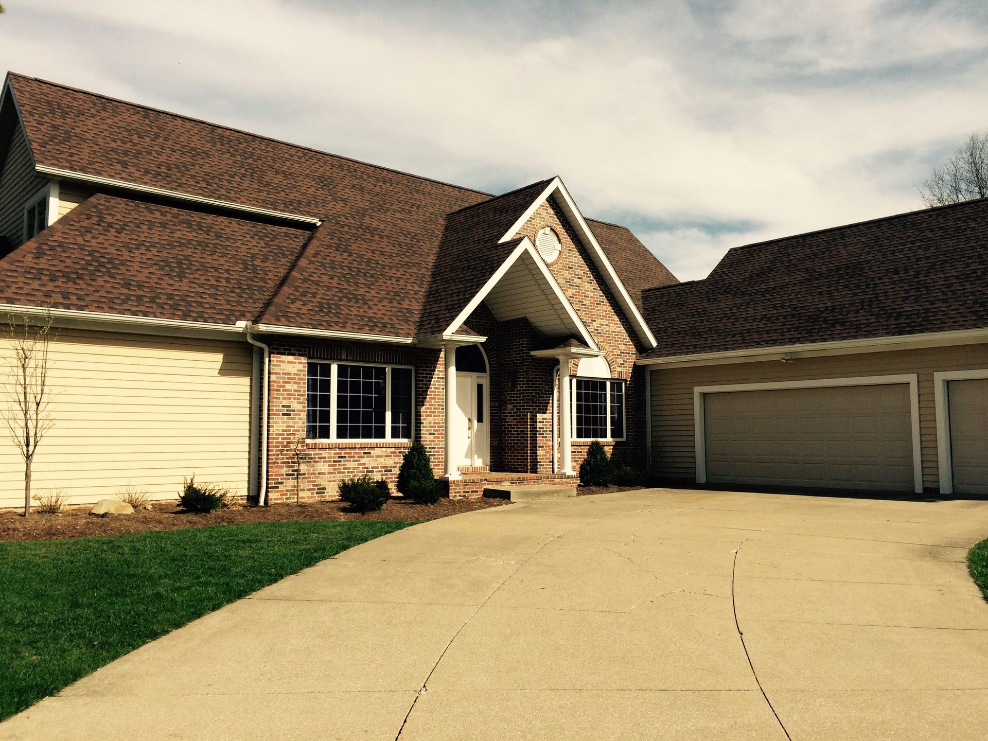 A large house with a brown roof and two garages
