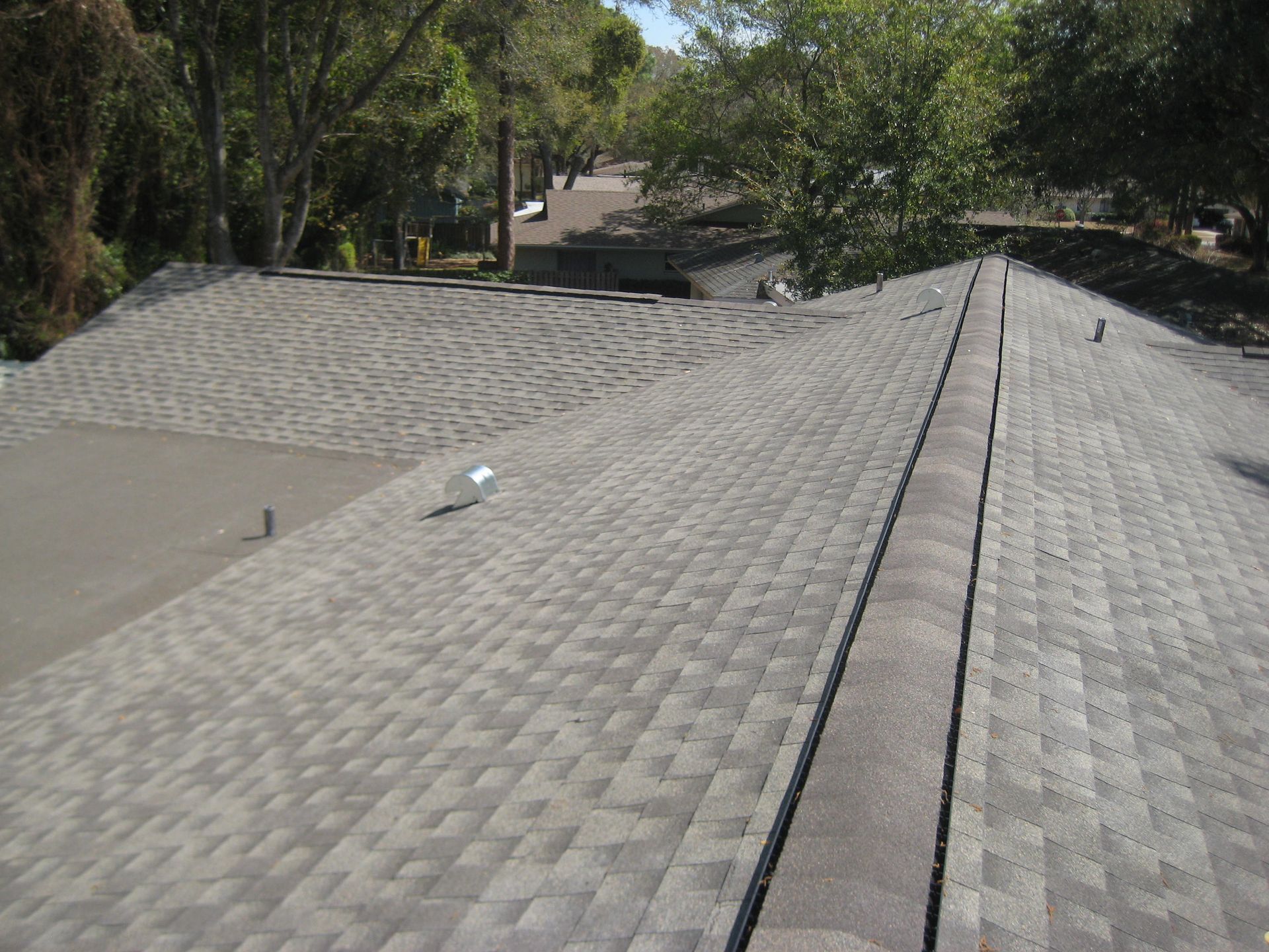 A roof with a lot of shingles and trees in the background