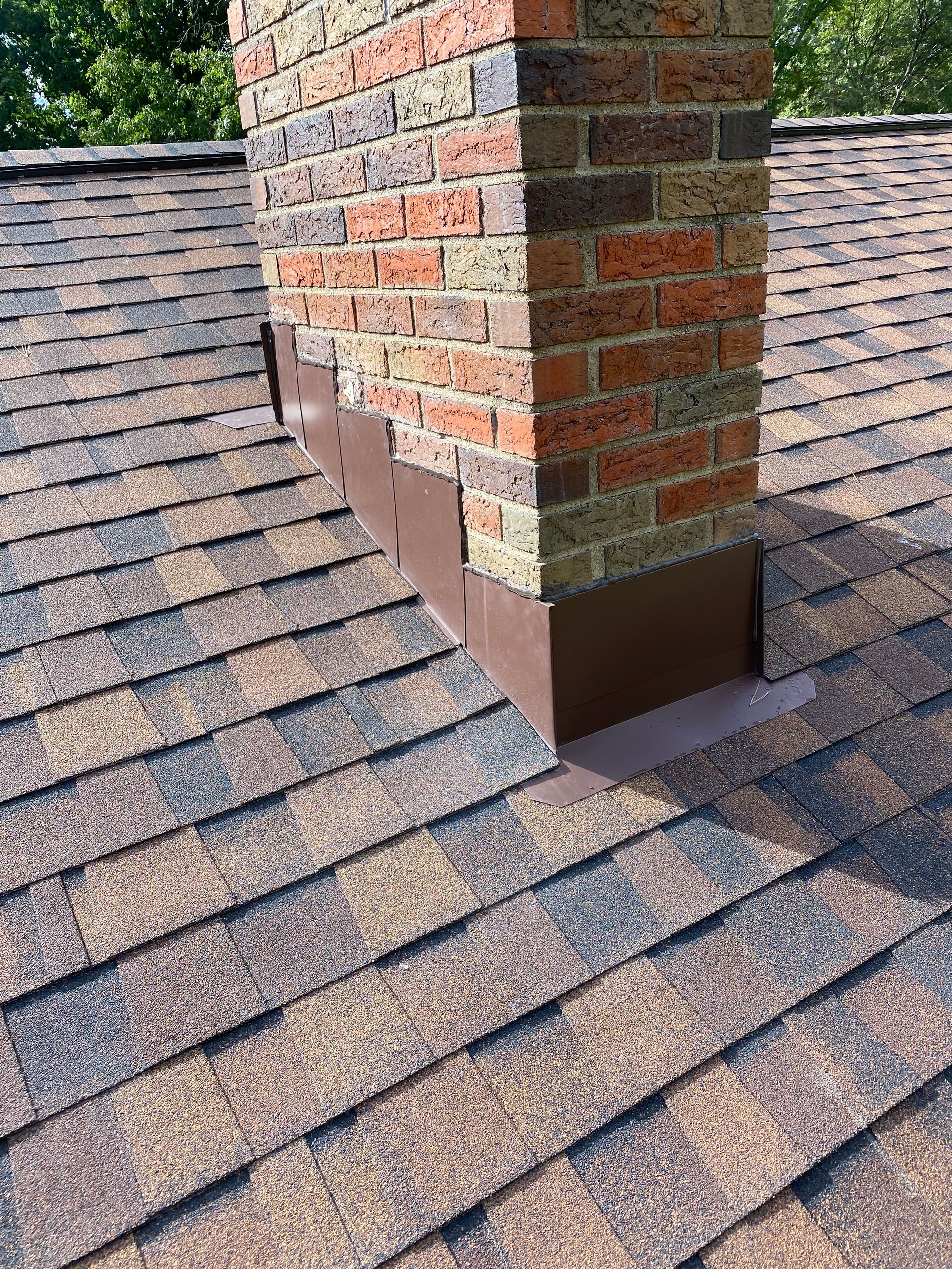 A brick chimney is sitting on top of a roof.