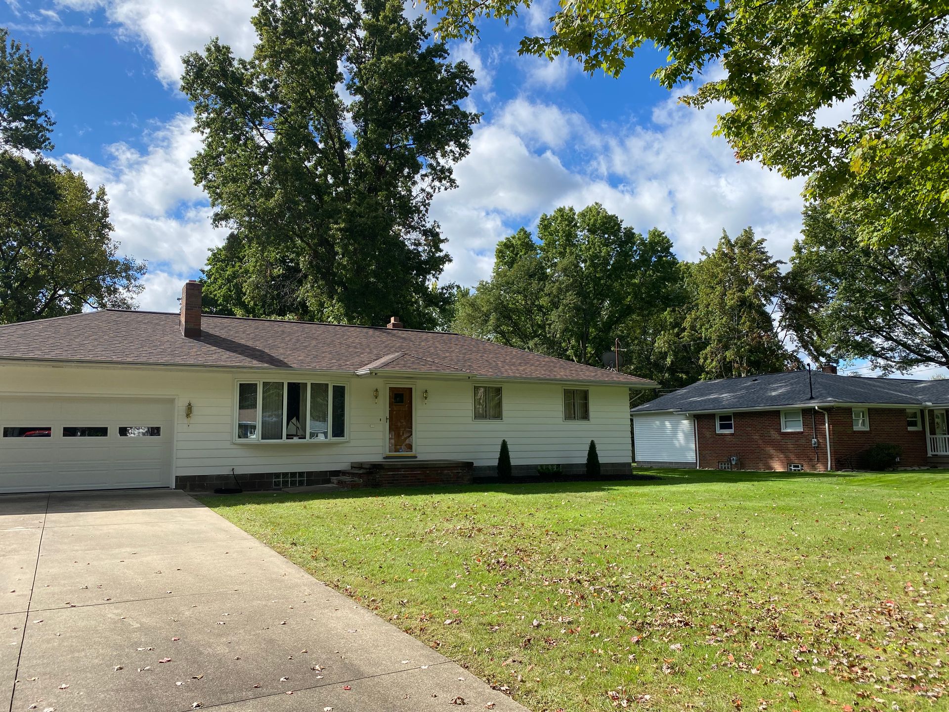 A white house with a brick house in the background