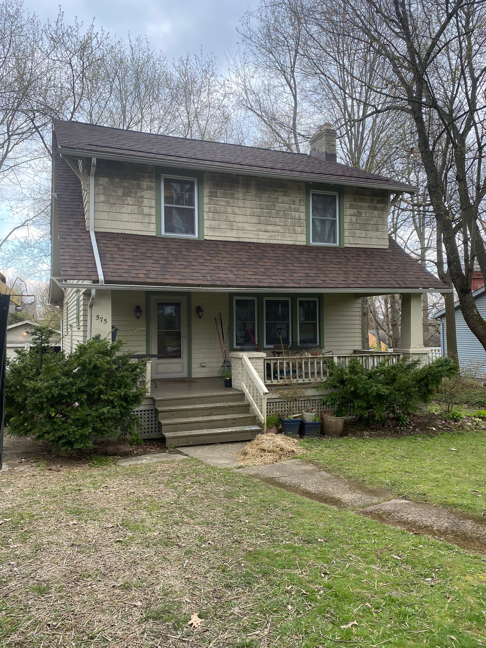 A large white brick house with a brown roof and a porch.