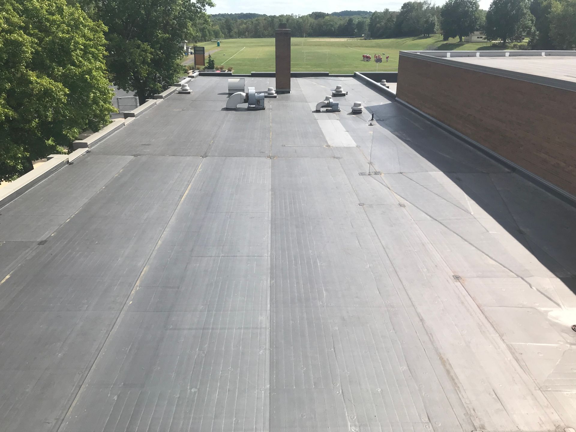 A roof with a chimney on it and a field in the background