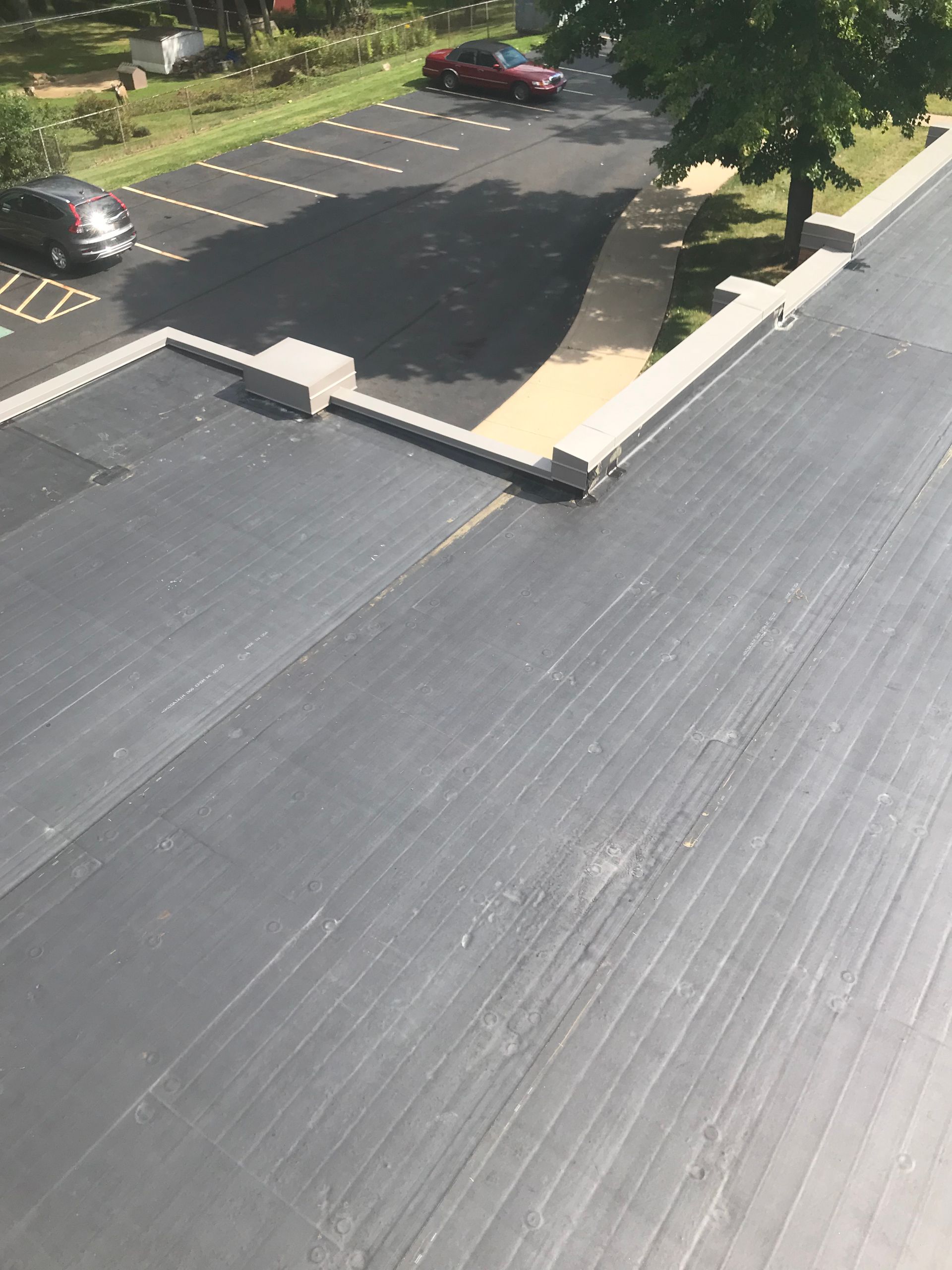 An aerial view of a roof with a parking lot in the background.