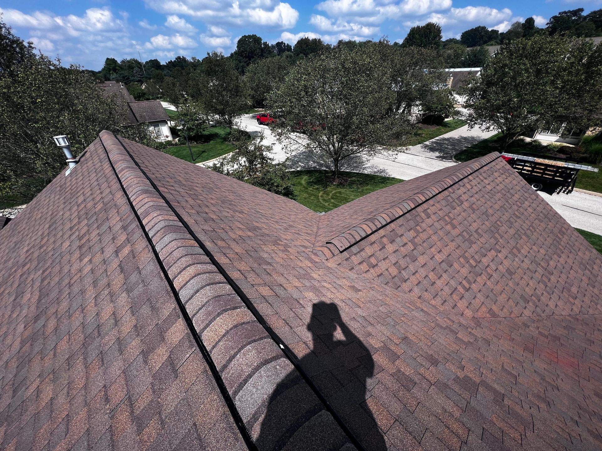 A shadow of a person is cast on the roof of a house.