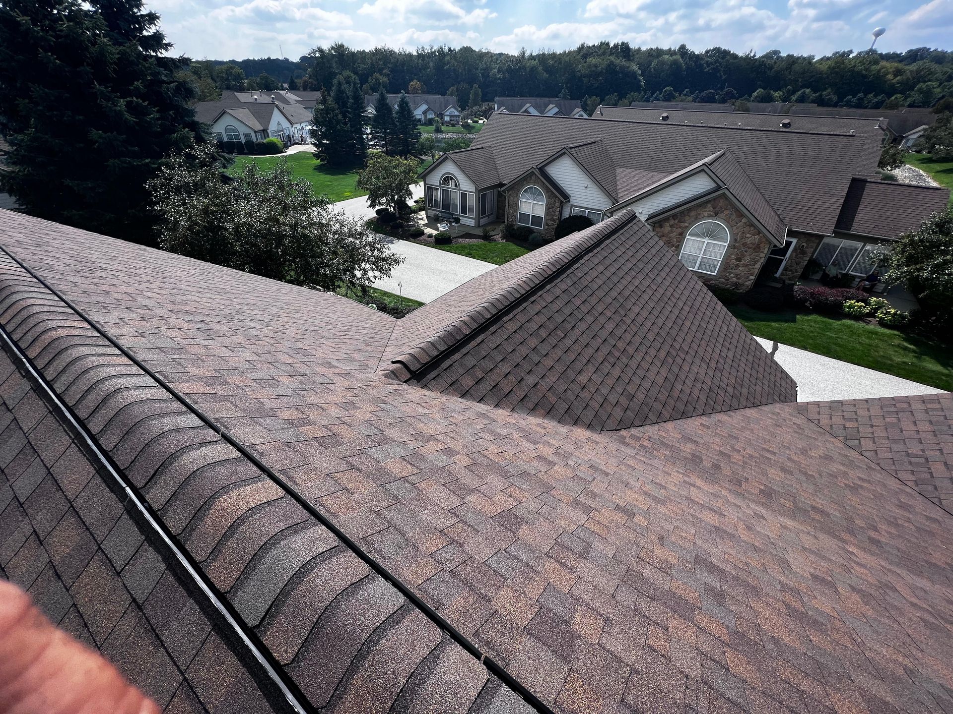 A person is standing on the roof of a house in a residential area.