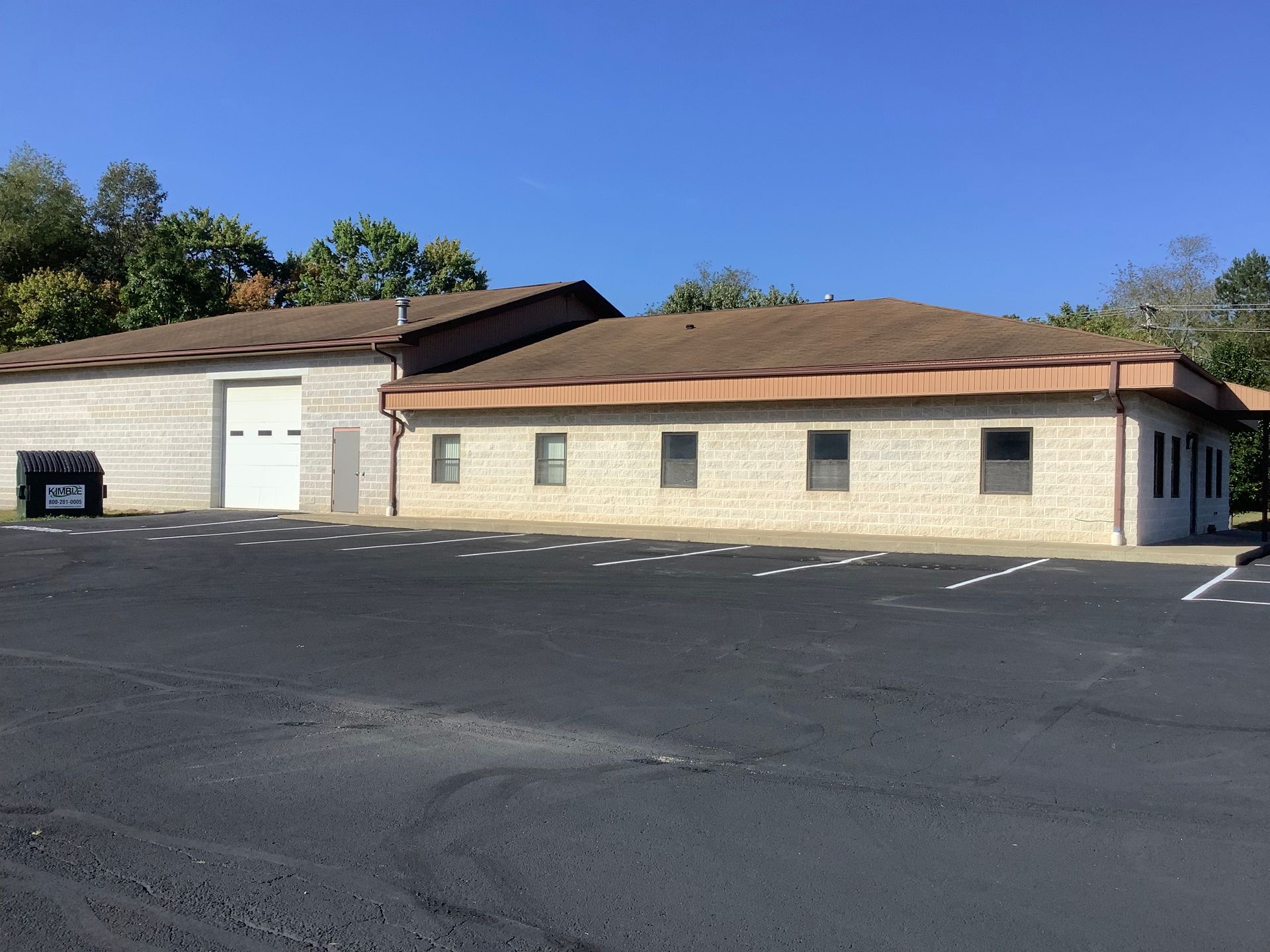 A brick building with a brown roof is sitting in a parking lot.