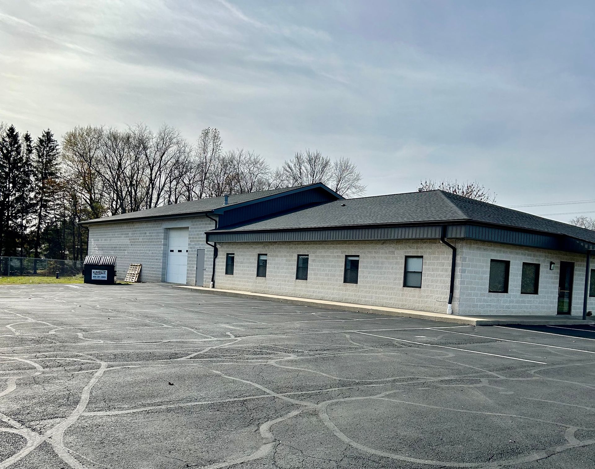 A large white building with a black roof is sitting in a parking lot.