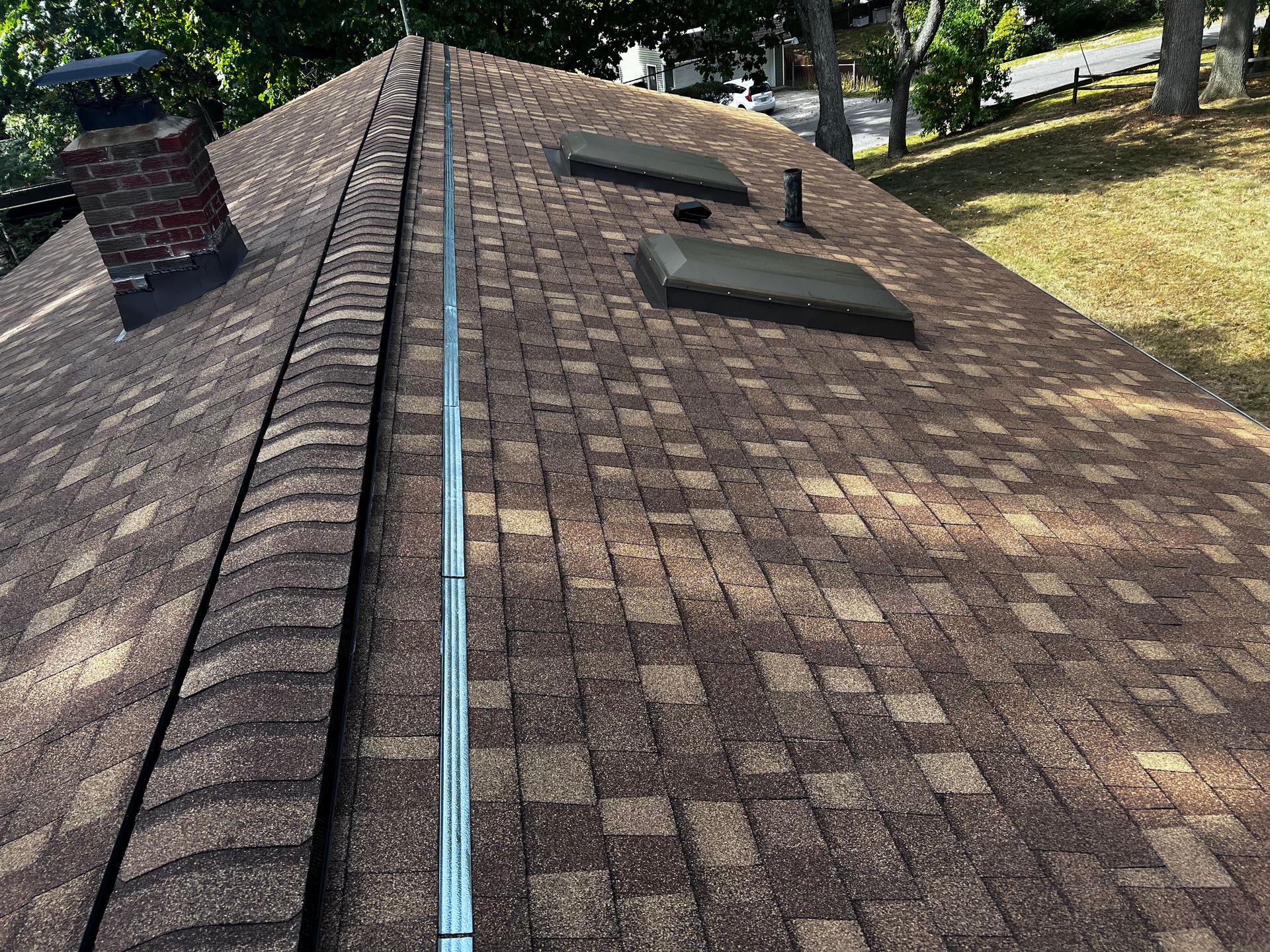 A roof with a chimney and skylights on it.