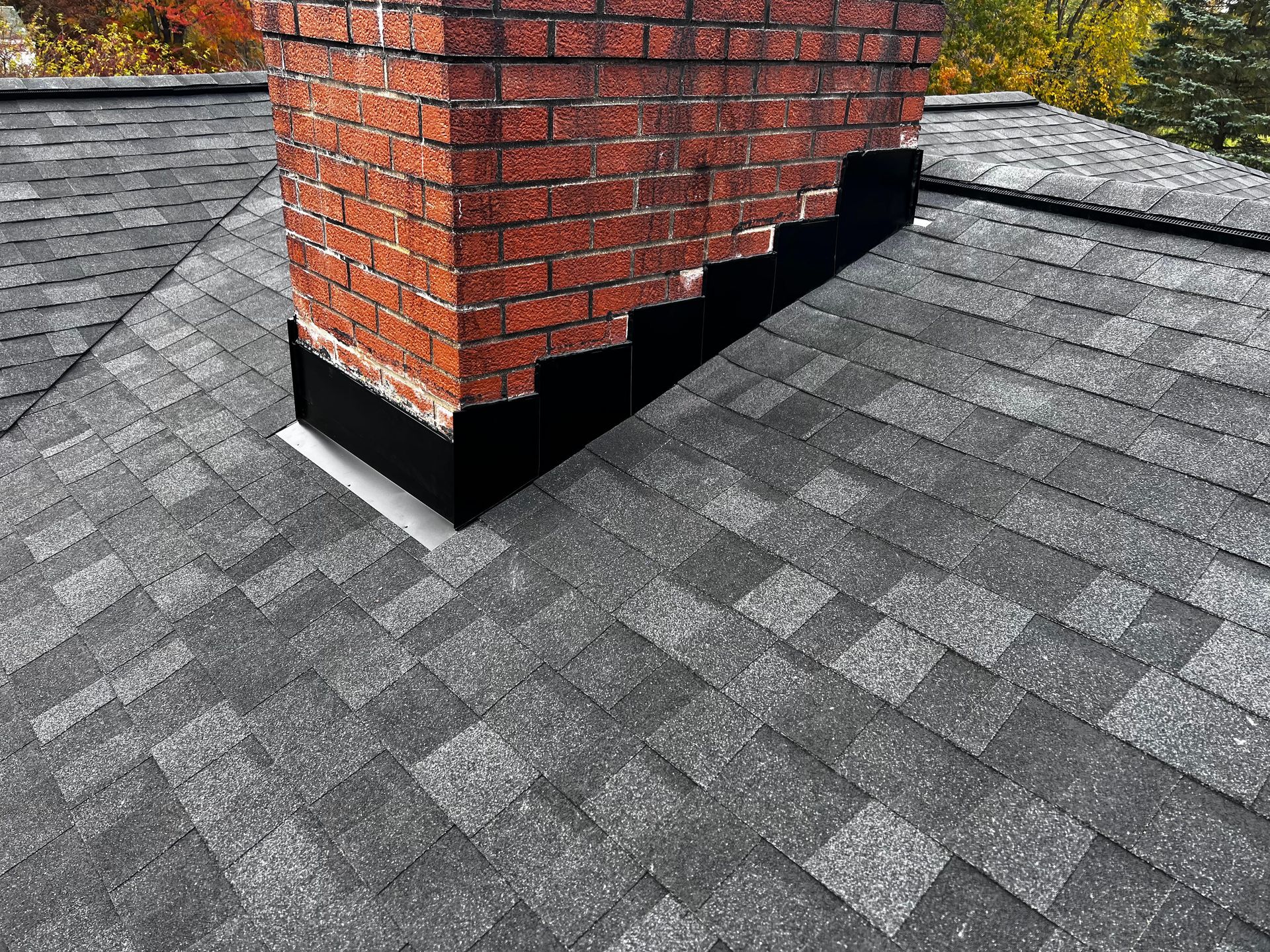 A brick chimney is sitting on top of a roof.