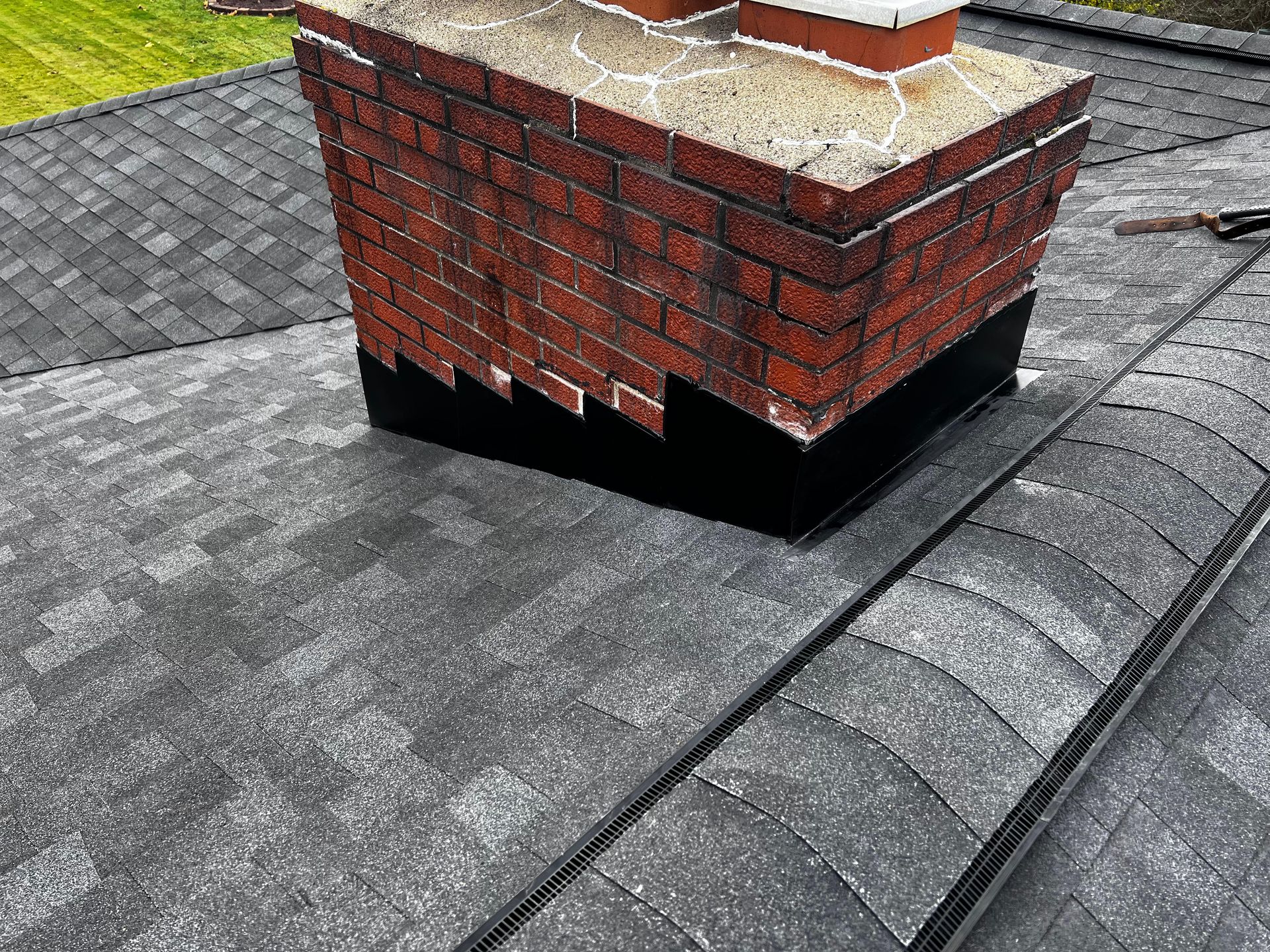 A brick chimney is sitting on top of a roof.