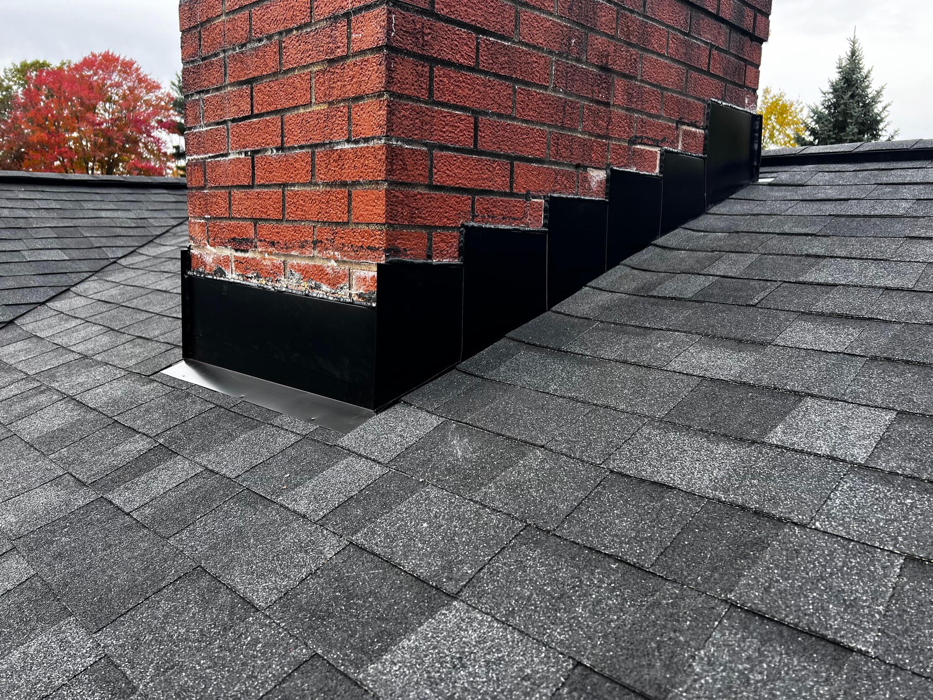 A brick chimney is sitting on top of a roof.