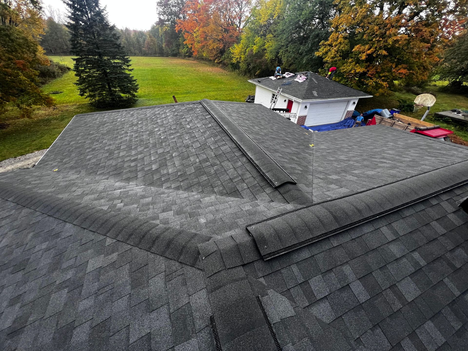 An aerial view of a roof with a house in the background.
