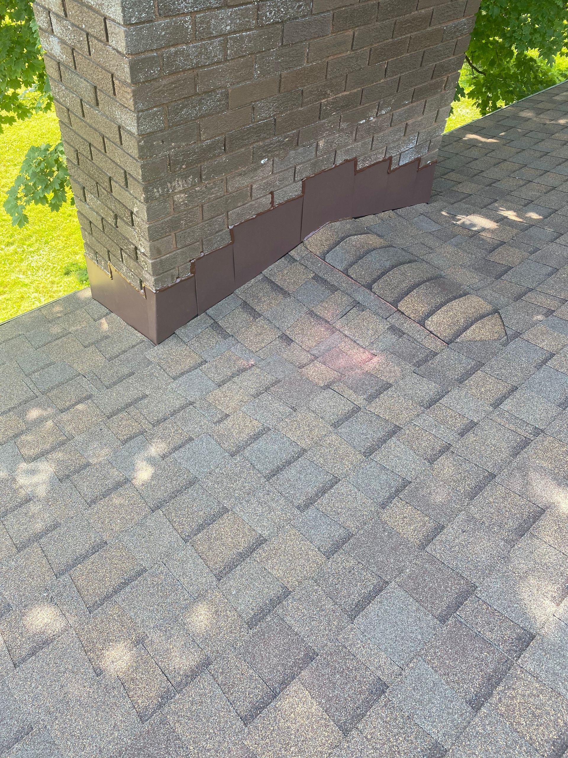 A chimney is sitting on top of a roof next to a brick wall.