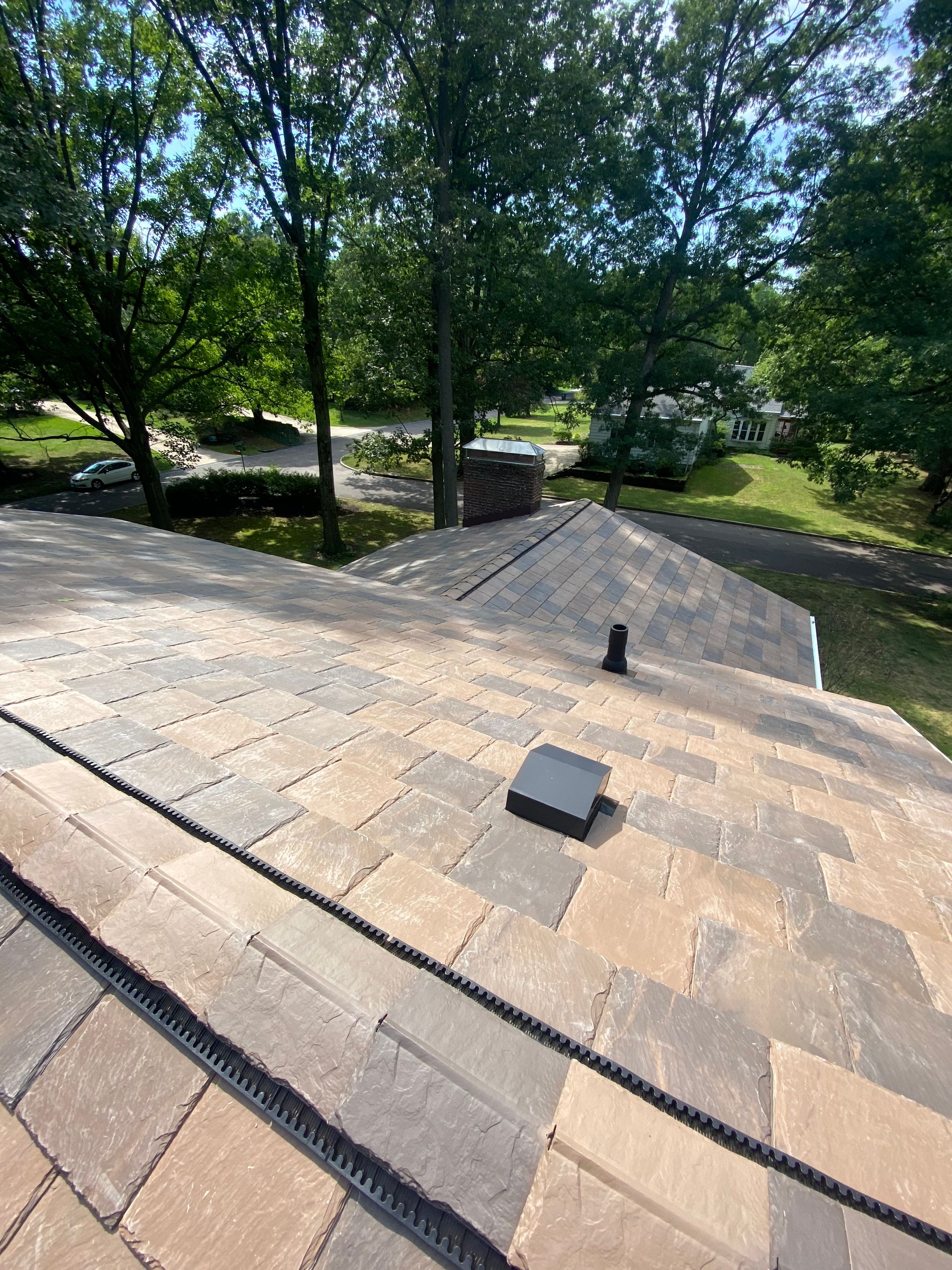 A roof with a chimney on it and trees in the background.