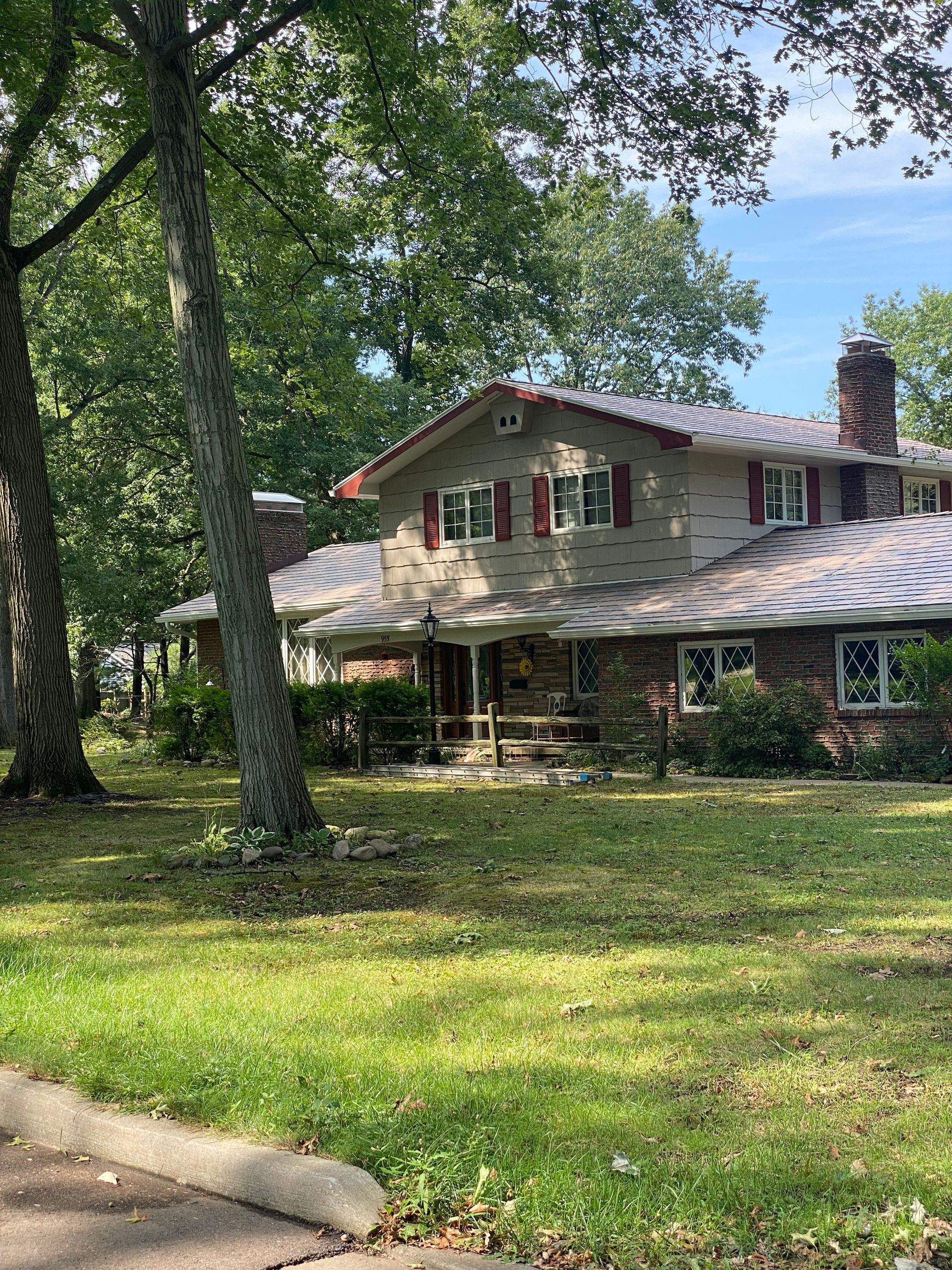 A large house with a large lawn in front of it is surrounded by trees.