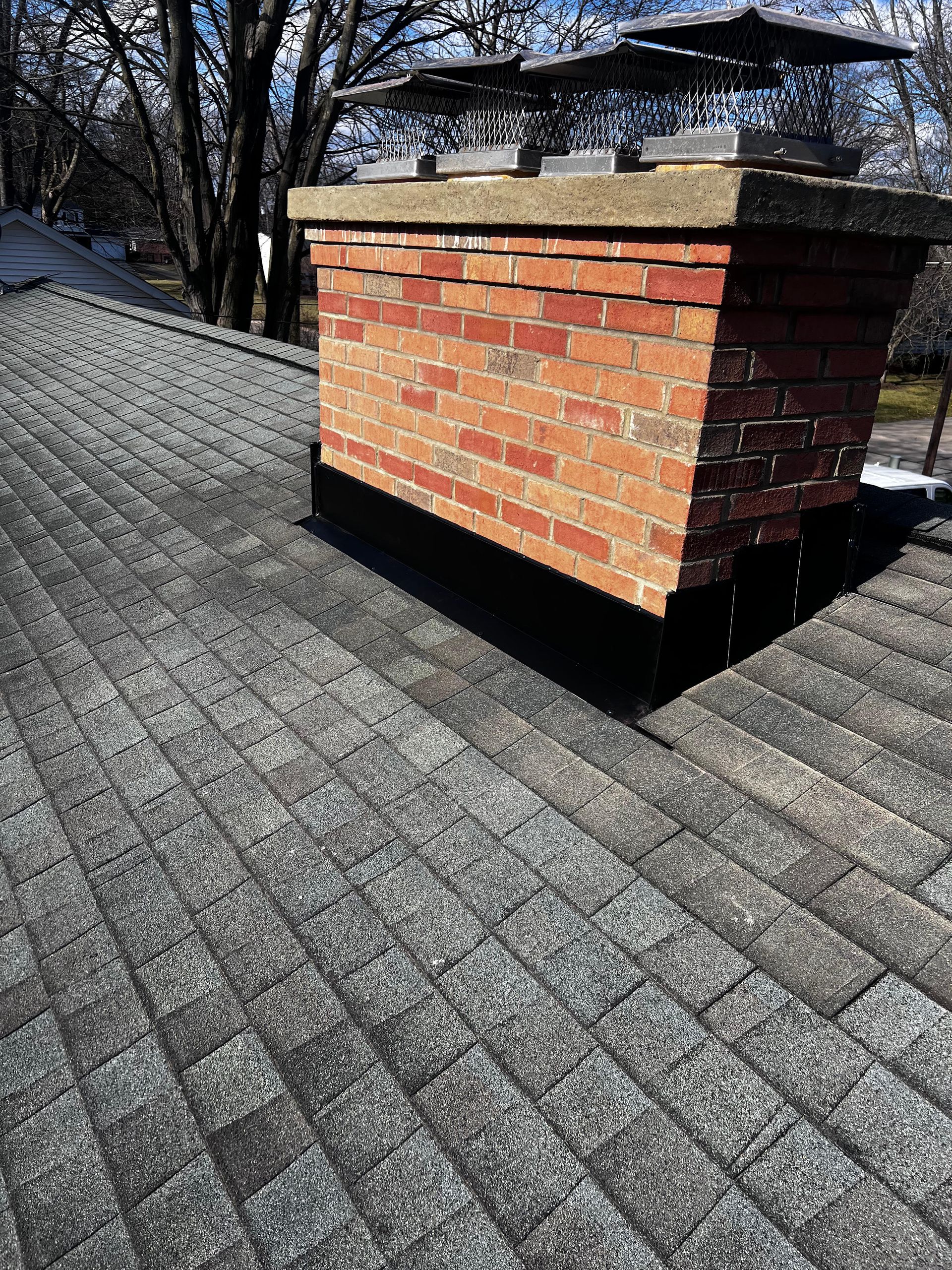 A brick chimney is sitting on top of a roof.