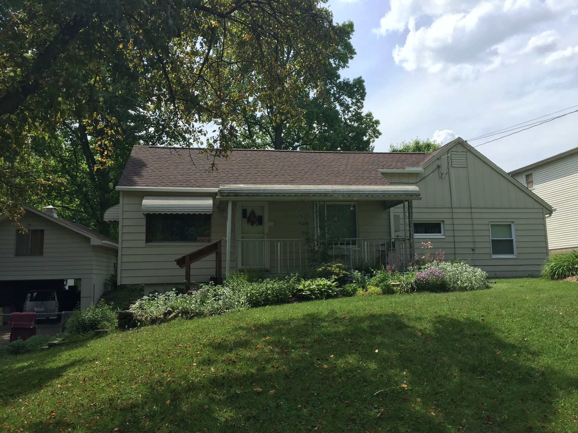 A small white house with a brown roof is sitting on top of a lush green hill.