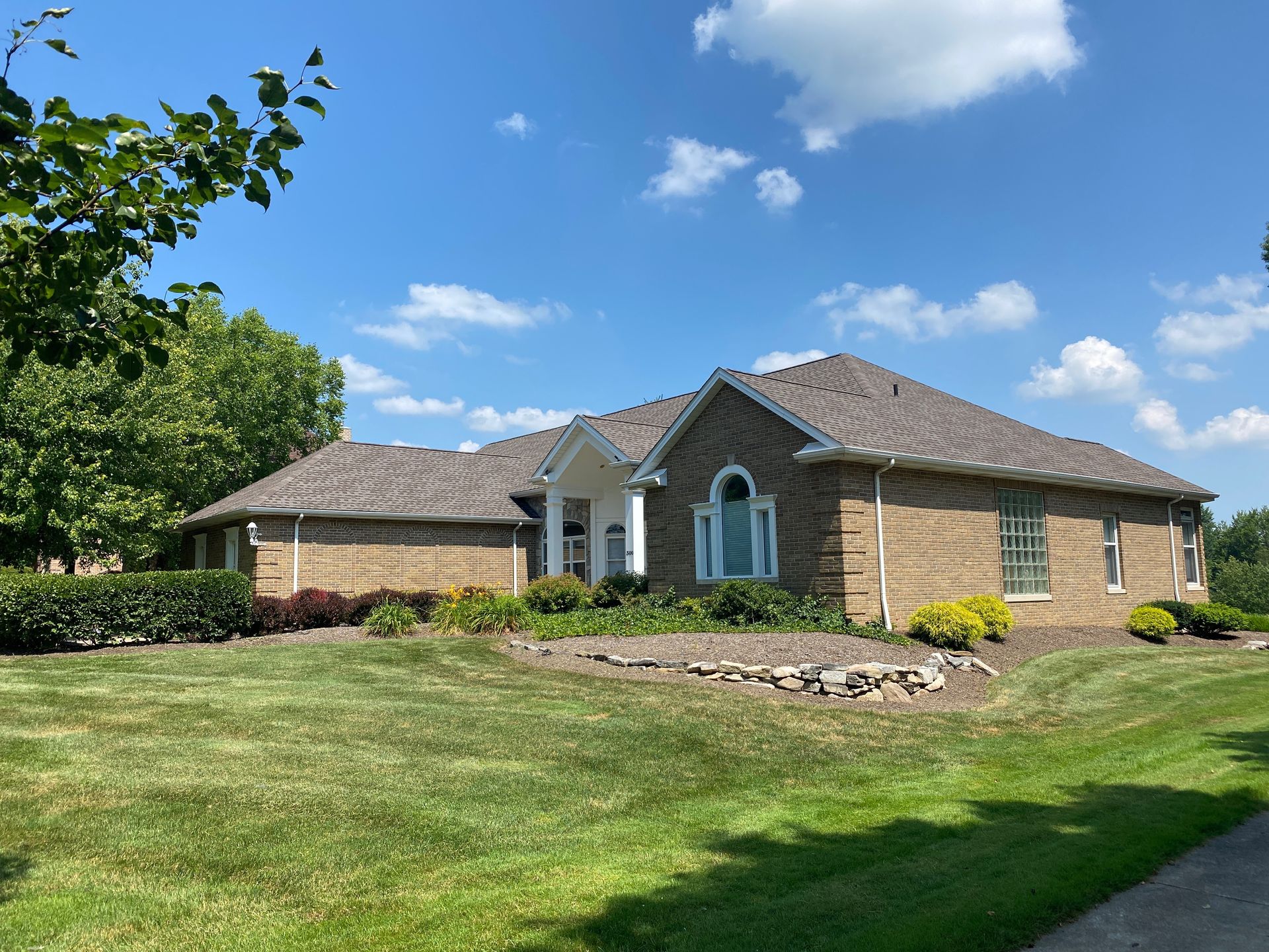 A large brick house with a large lawn in front of it