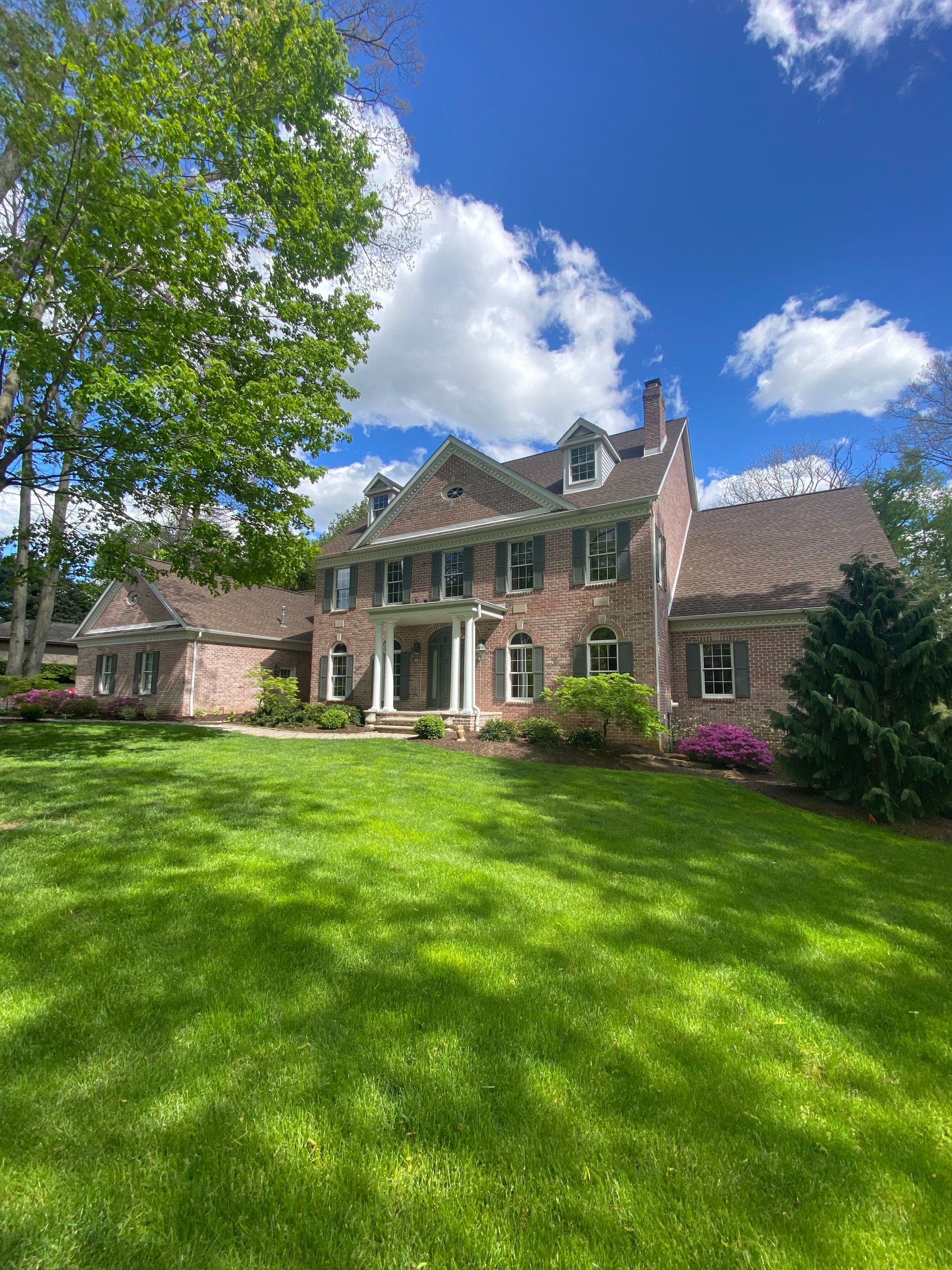 A large brick house with a large lush green lawn in front of it.