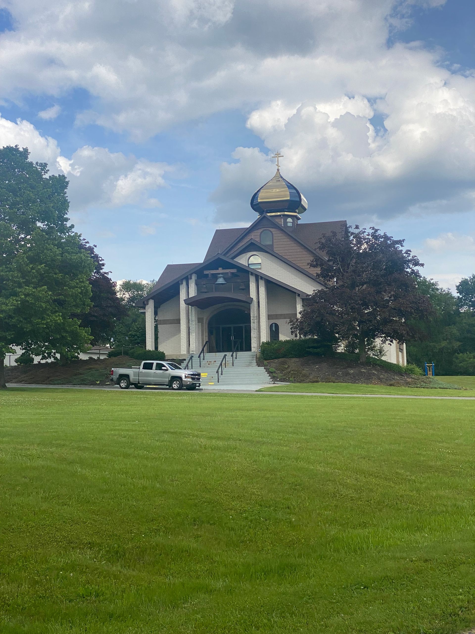 A white truck is parked in front of a church.