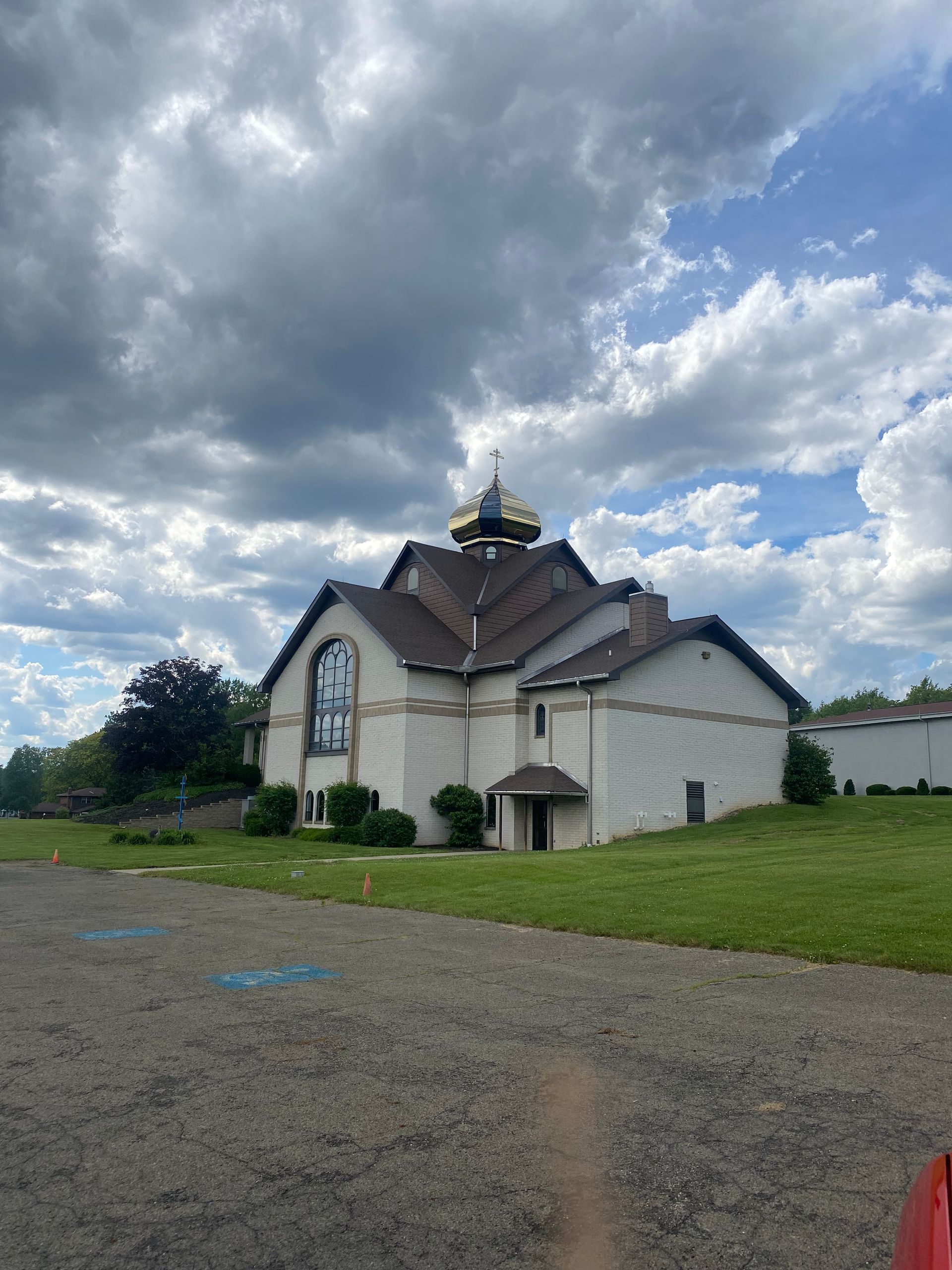 A large white building with a brown roof is sitting in the middle of a grassy field.