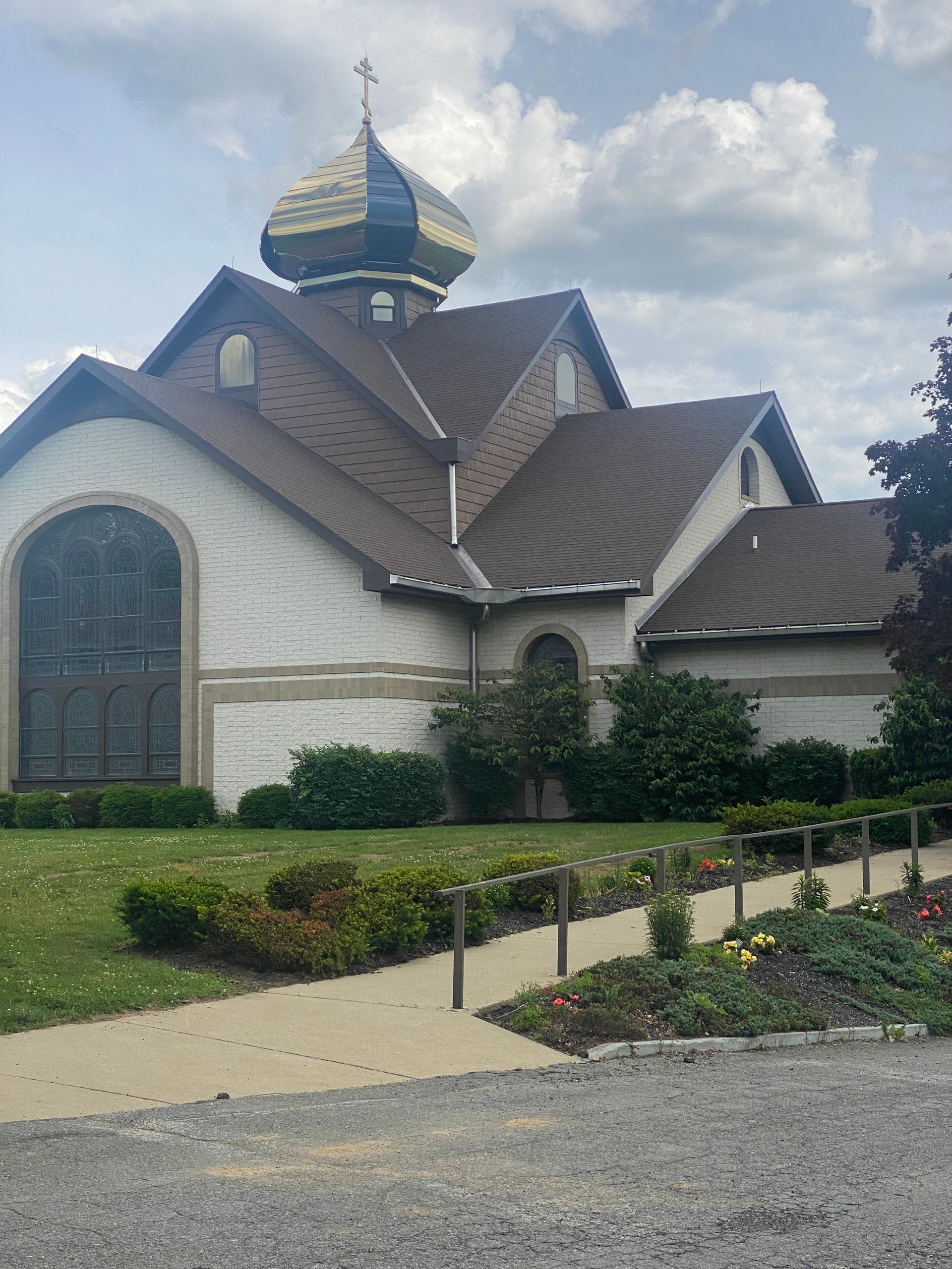 A large white church with a brown roof and a stained glass window.