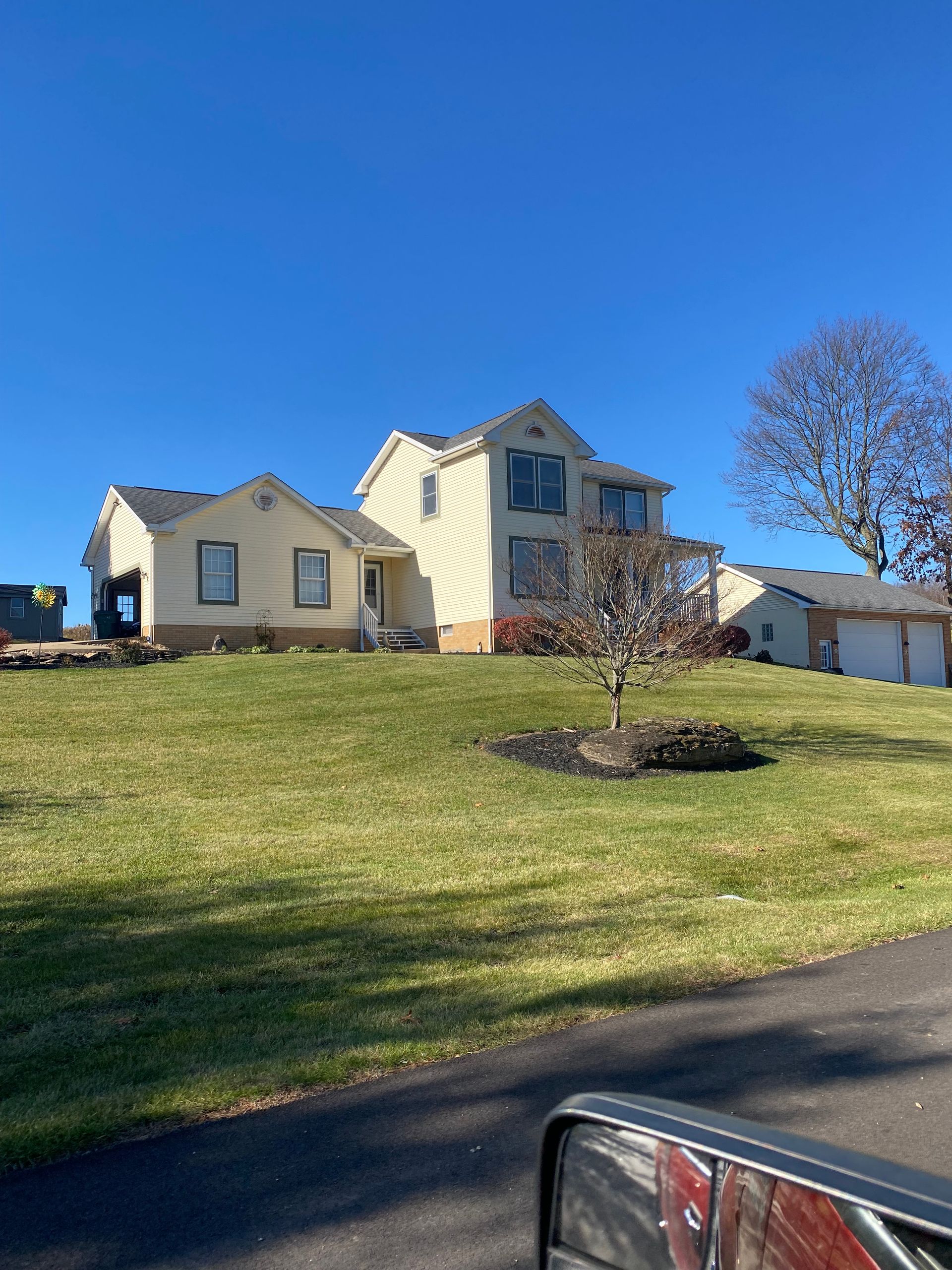 A large house is sitting on top of a lush green hill.