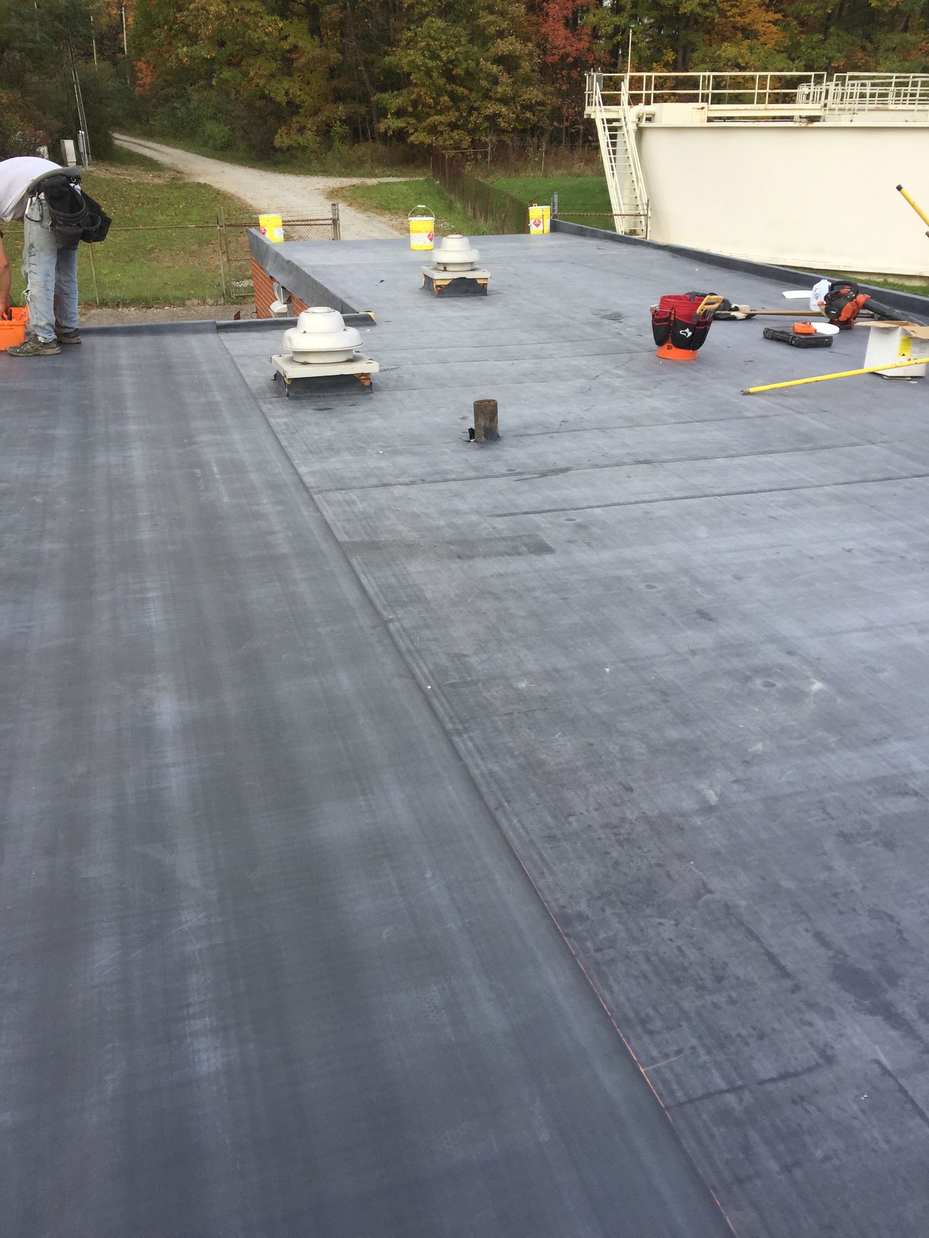 A man is standing on top of a black roof.