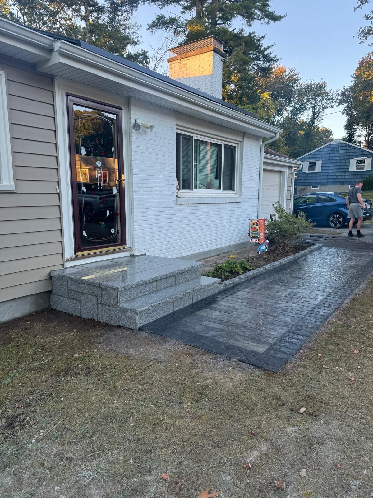A house exterior featuring a new gray stone entryway with steps and a matching paved walkway.