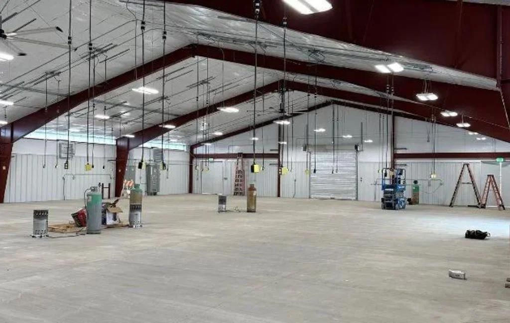 A large empty warehouse with a concrete floor and ceiling fans.