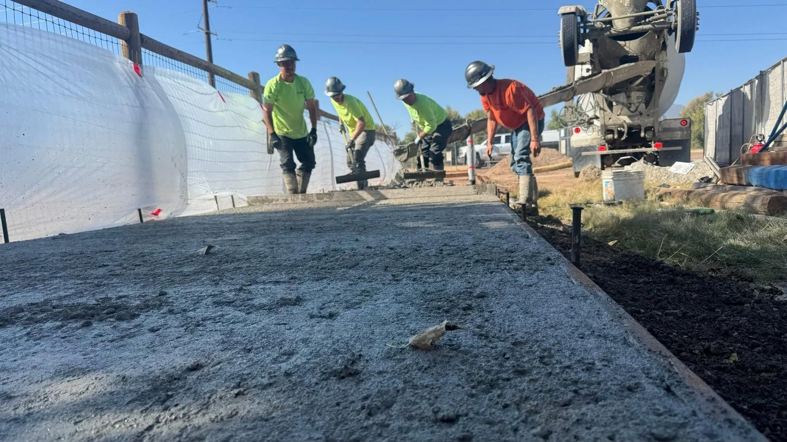A group of construction workers are working on a sidewalk.
