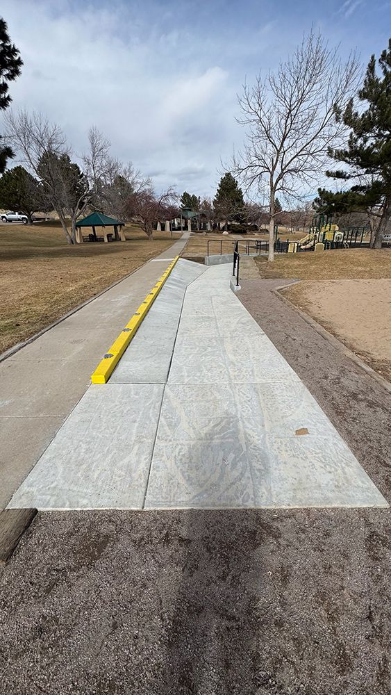 A concrete walkway with a yellow line on it in a park.