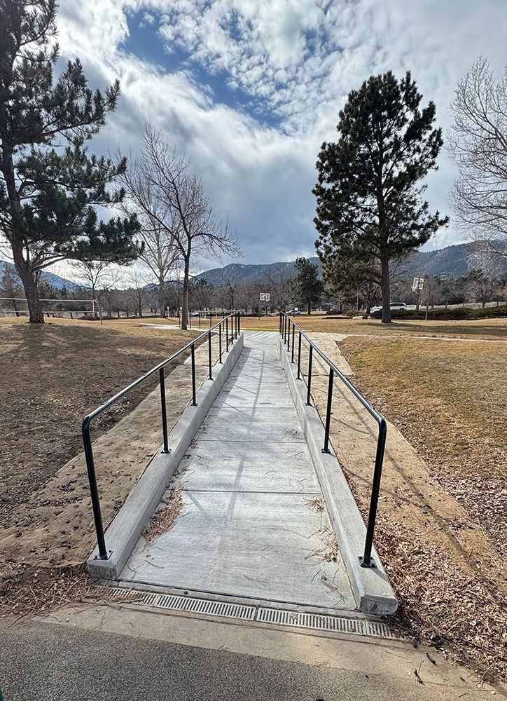 A handicapped ramp in a park with trees and mountains in the background.