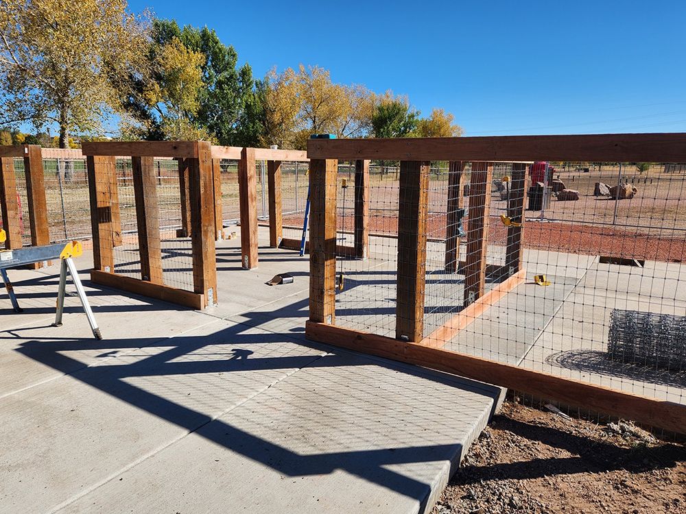 A wooden fence is being built on a concrete sidewalk.