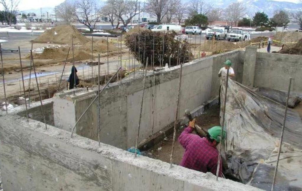 A man wearing a hard hat is working on a concrete wall