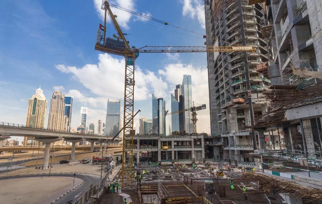 A construction site with a lot of cranes and buildings in the background.