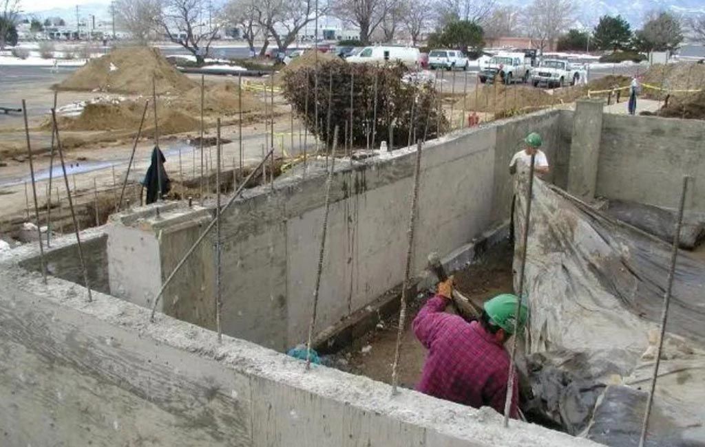 A man wearing a hard hat is working on a concrete wall