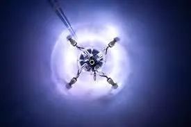 Glowing robotic drone with four arms against a purple-blue background