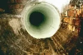 Circular tunnel opening in a rough brown wall, viewed from above.